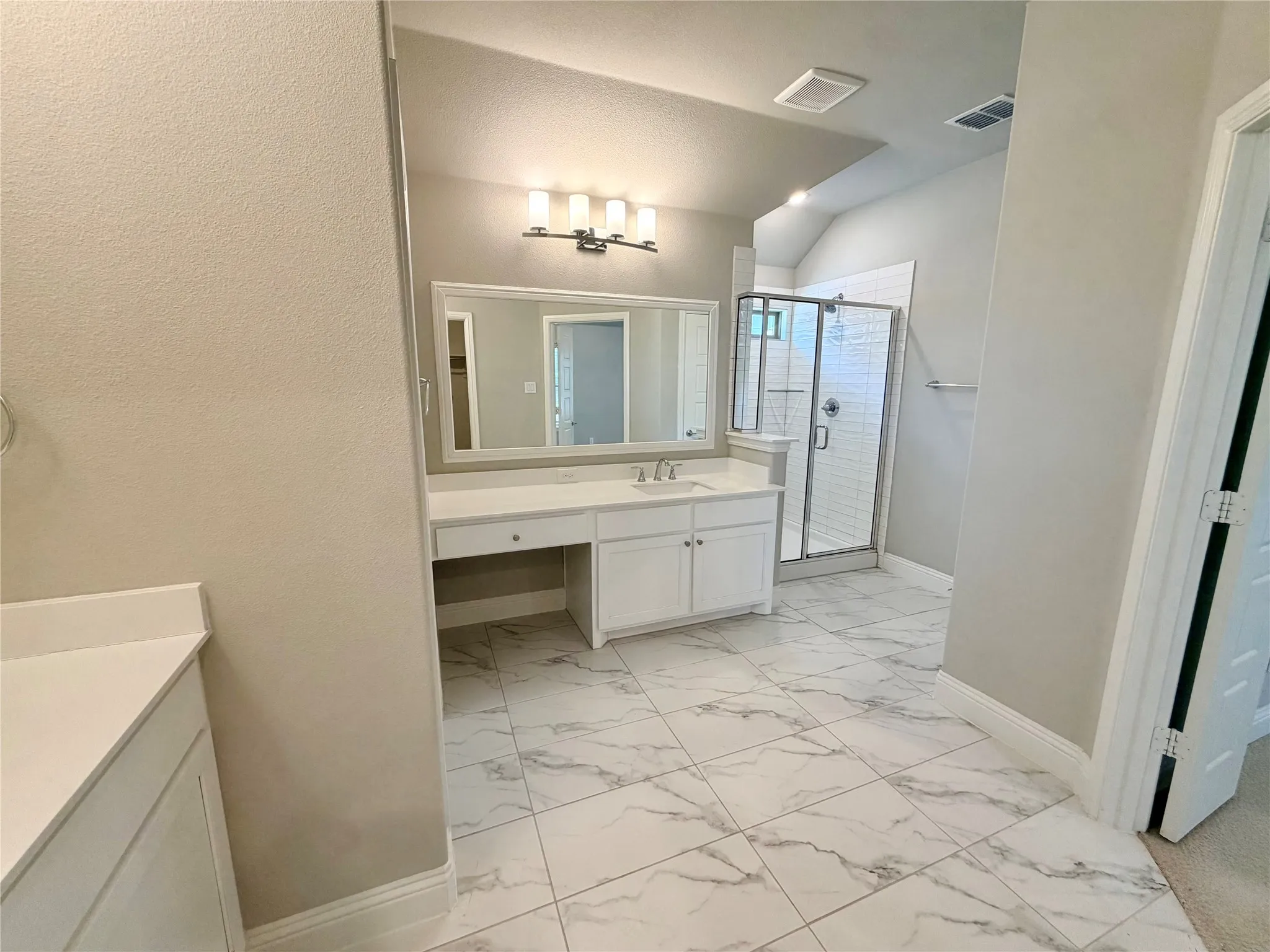 White vanity with undermount sink, a large mirror, and a wall-mounted light fixture