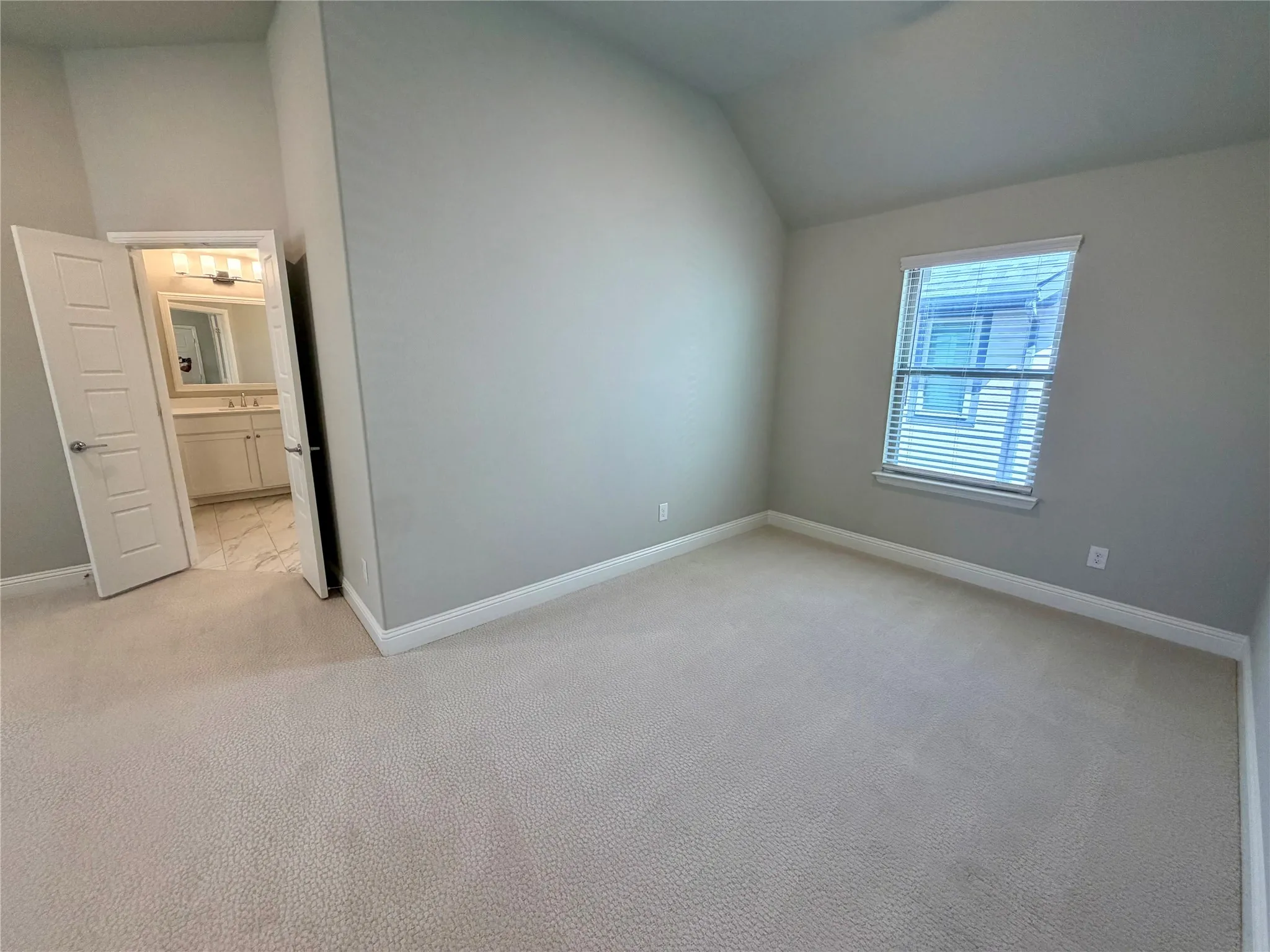 Carpeted room with a window featuring blinds, a neutral wall color, and a high ceiling