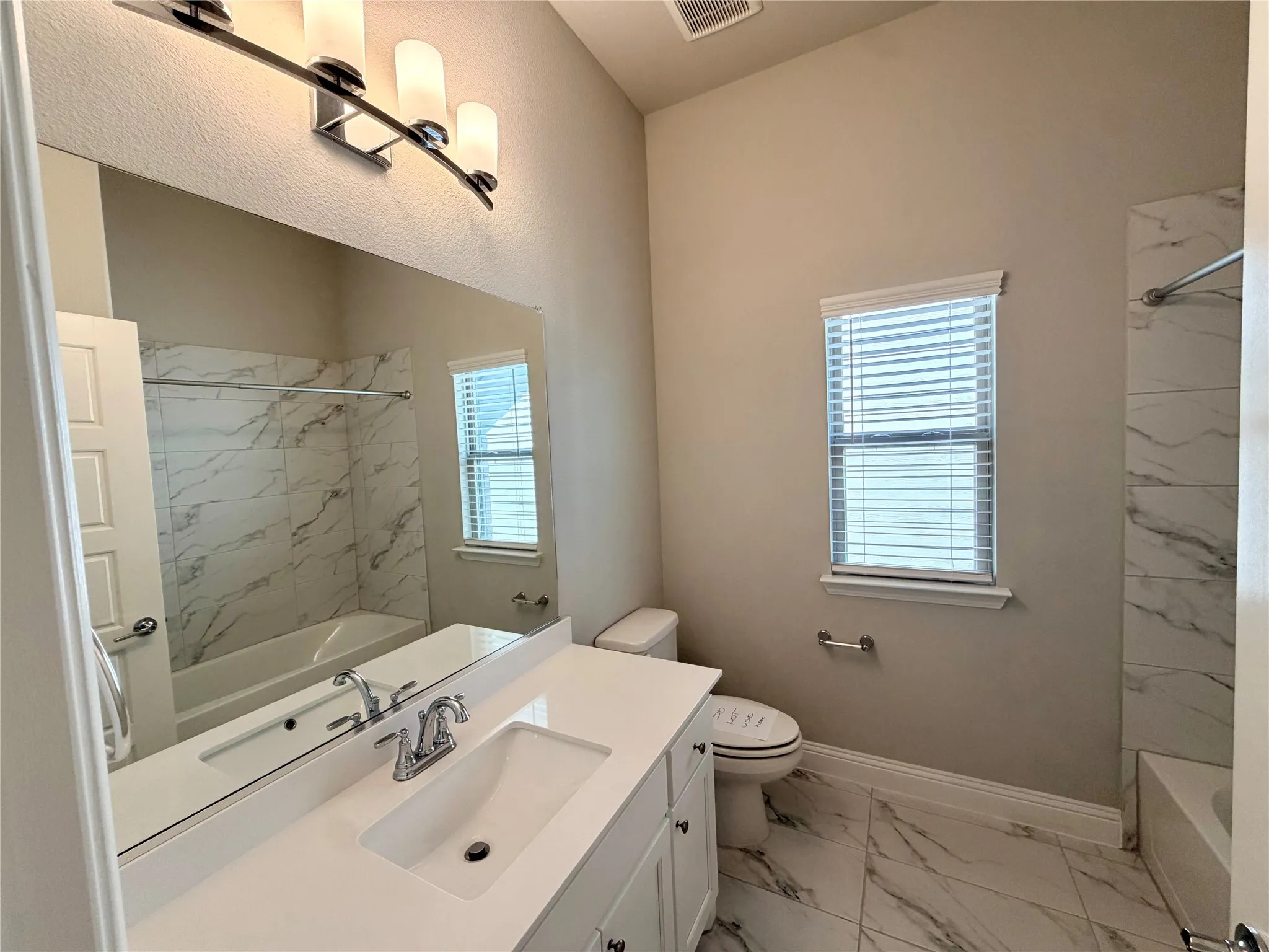 White vanity with an integrated sink, polished chrome faucet, and expansive wall-mounted mirror