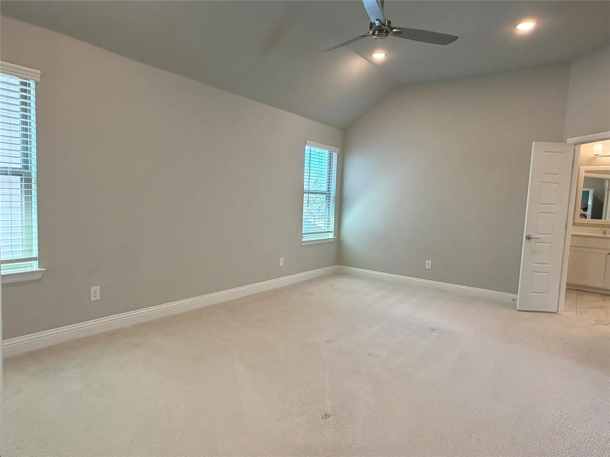 Vaulted ceiling with recessed lighting and a ceiling fan, dual windows with blinds, and neutral carpeting
