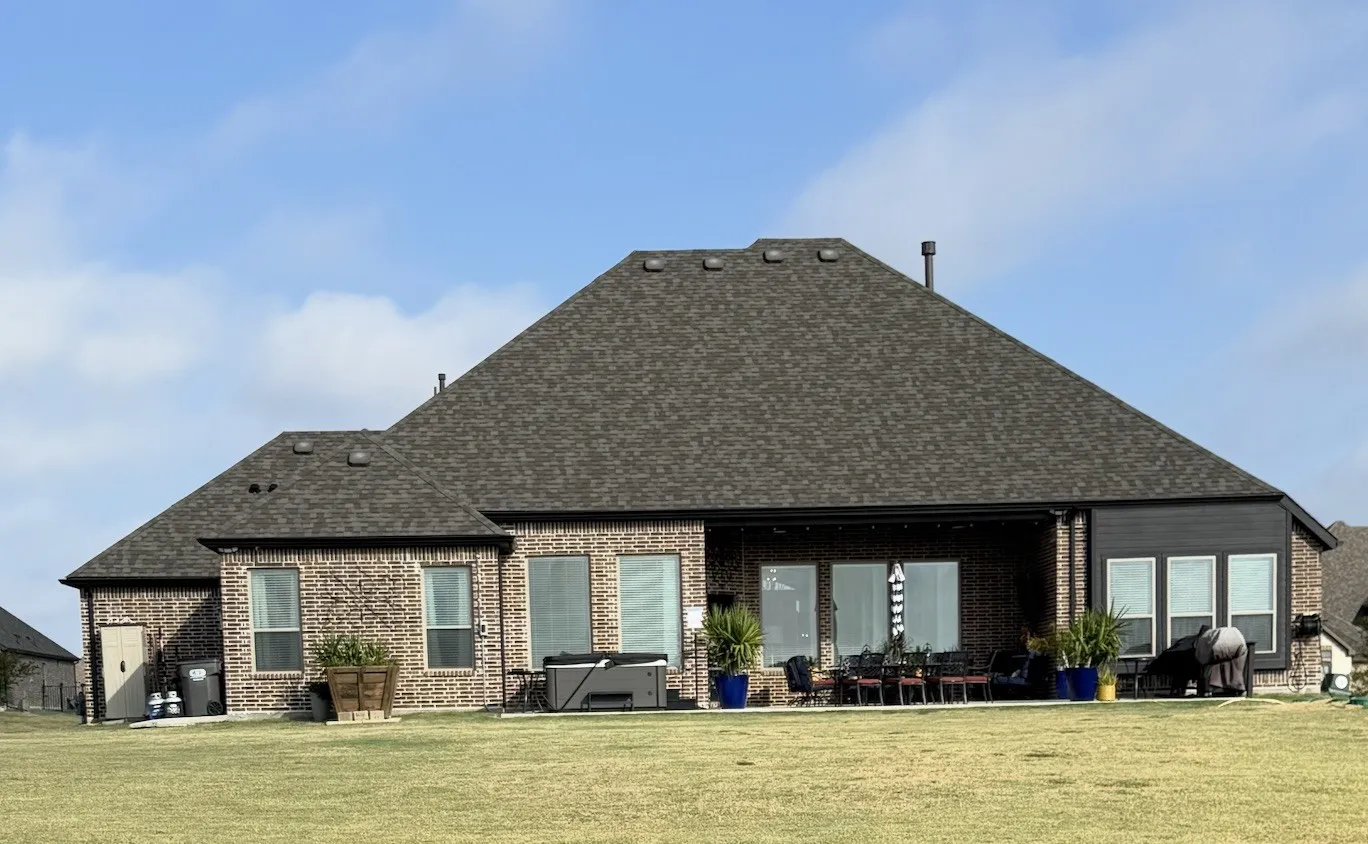 Expansive backyard featuring a manicured lawn, full brick exterior, large patio, and ample windows