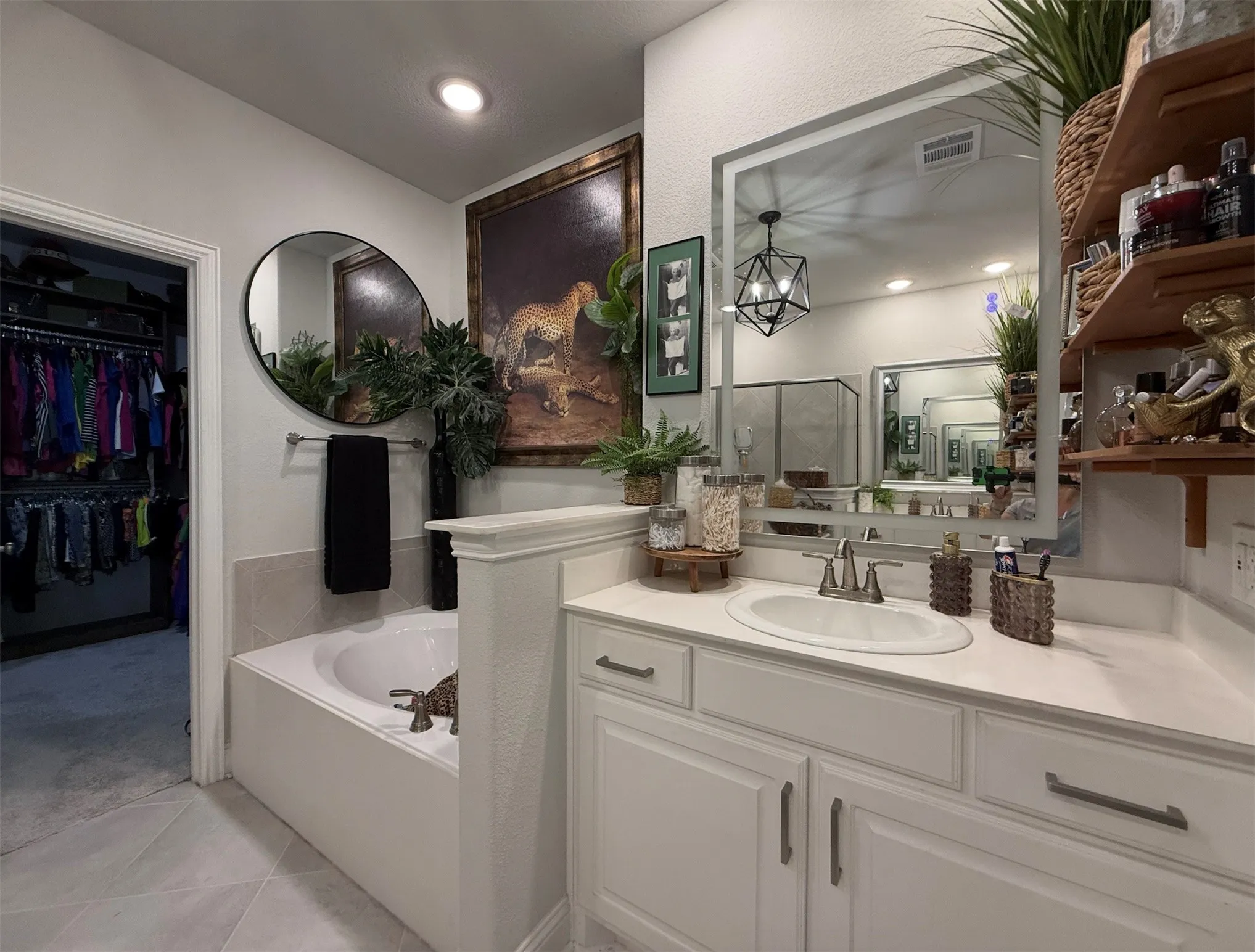 White vanity with an integrated sink and brushed nickel faucet, a large framed mirror, and built-in shelving