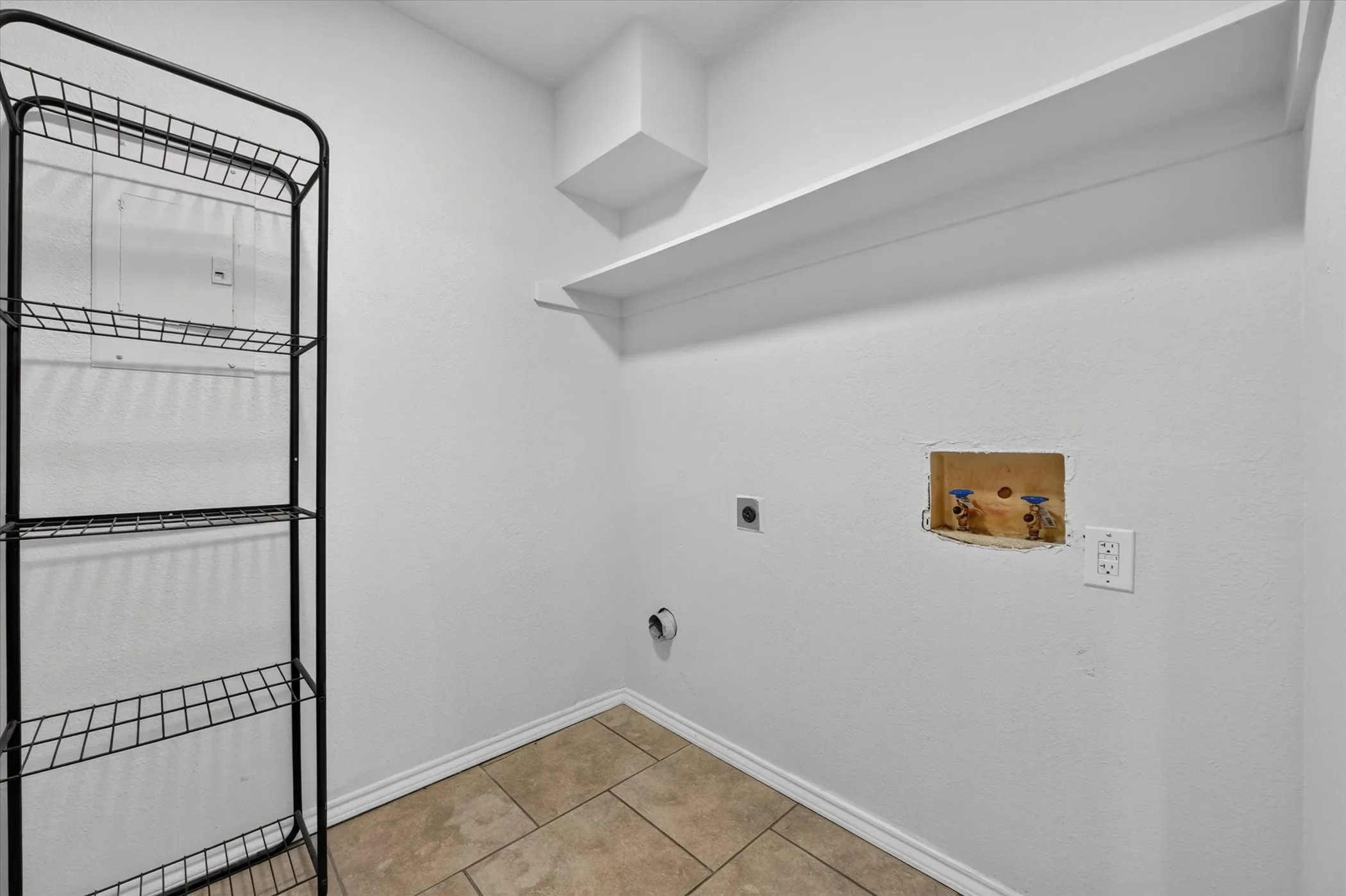 Laundry room has room for full-sized washer & dryer, with a shelf for supplies above.