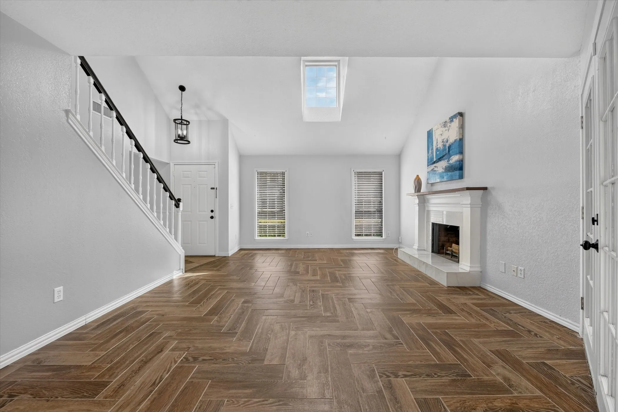 Vaulted ceiling with a skylight, white fireplace & mantel.