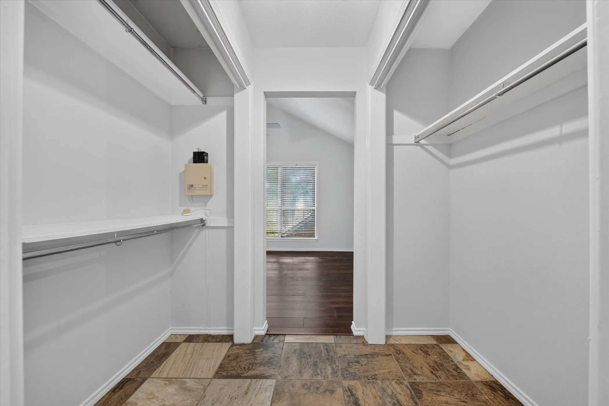 Primary closet space between primary bedroom & bathroom with shelving, and hanging rods. There is a second closet in the bedroom.