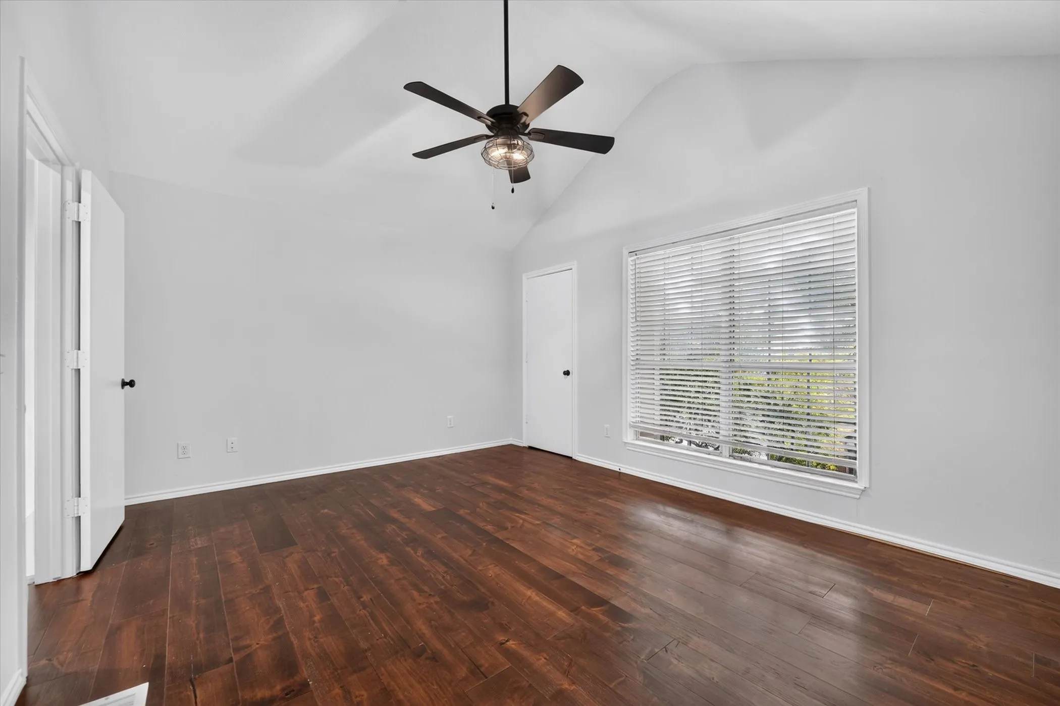 Primary bedroom has vaulted ceiling, engineered wood flooring, and a ceiling fan with light fixture