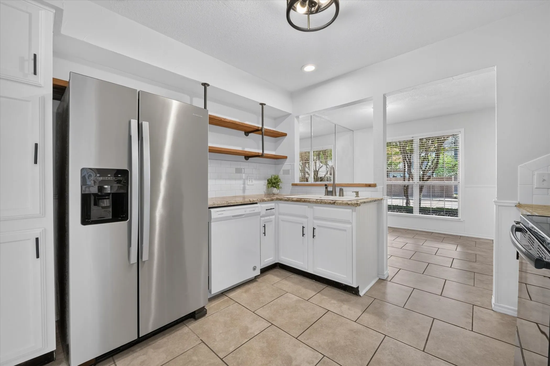 Kitchen featuring white cabinetry, natural countertops, stainless steel refrigerator, open shelving, and tile flooring