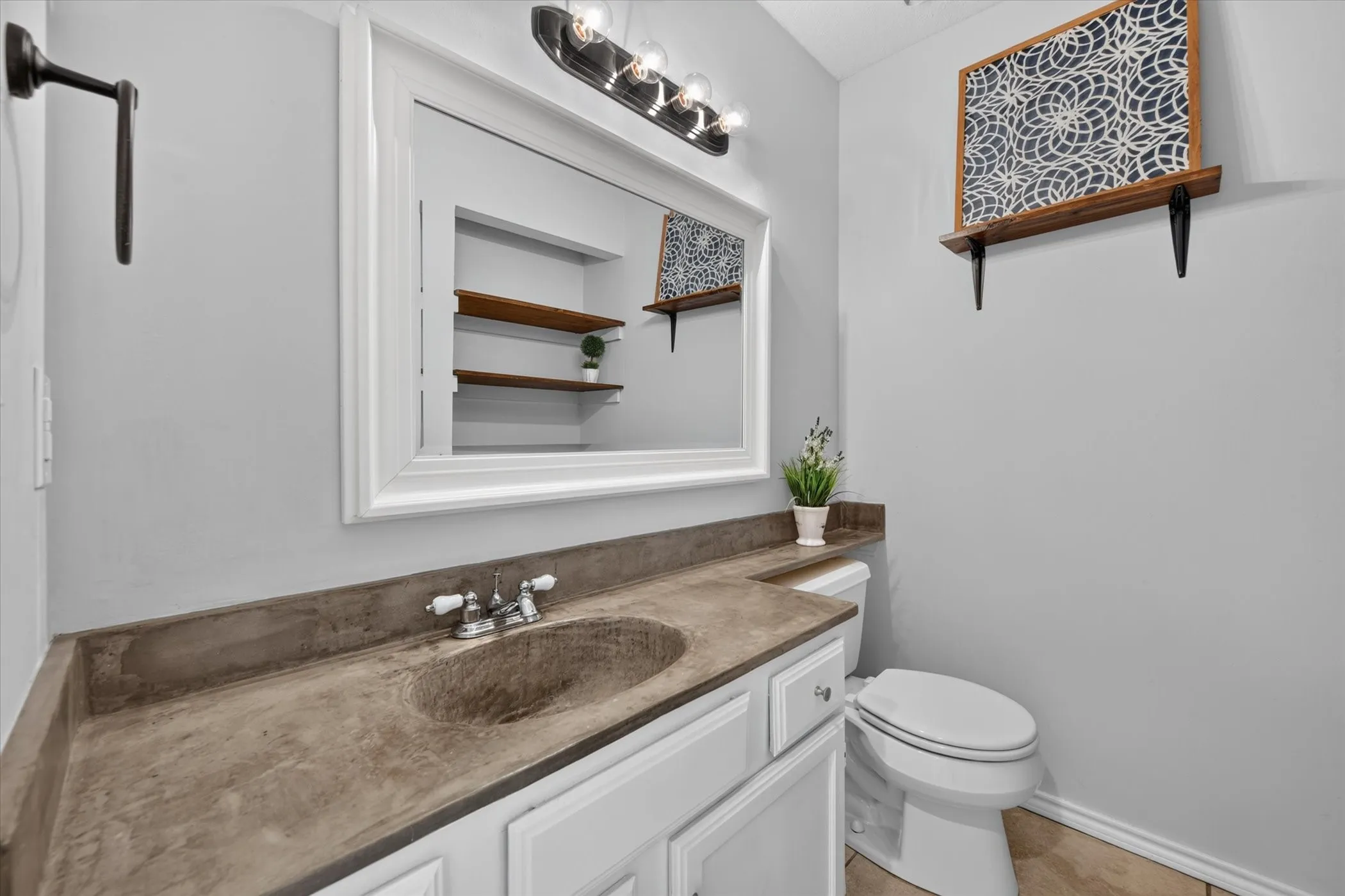 Spacious half bath downstairs has shelves for storage or decor.