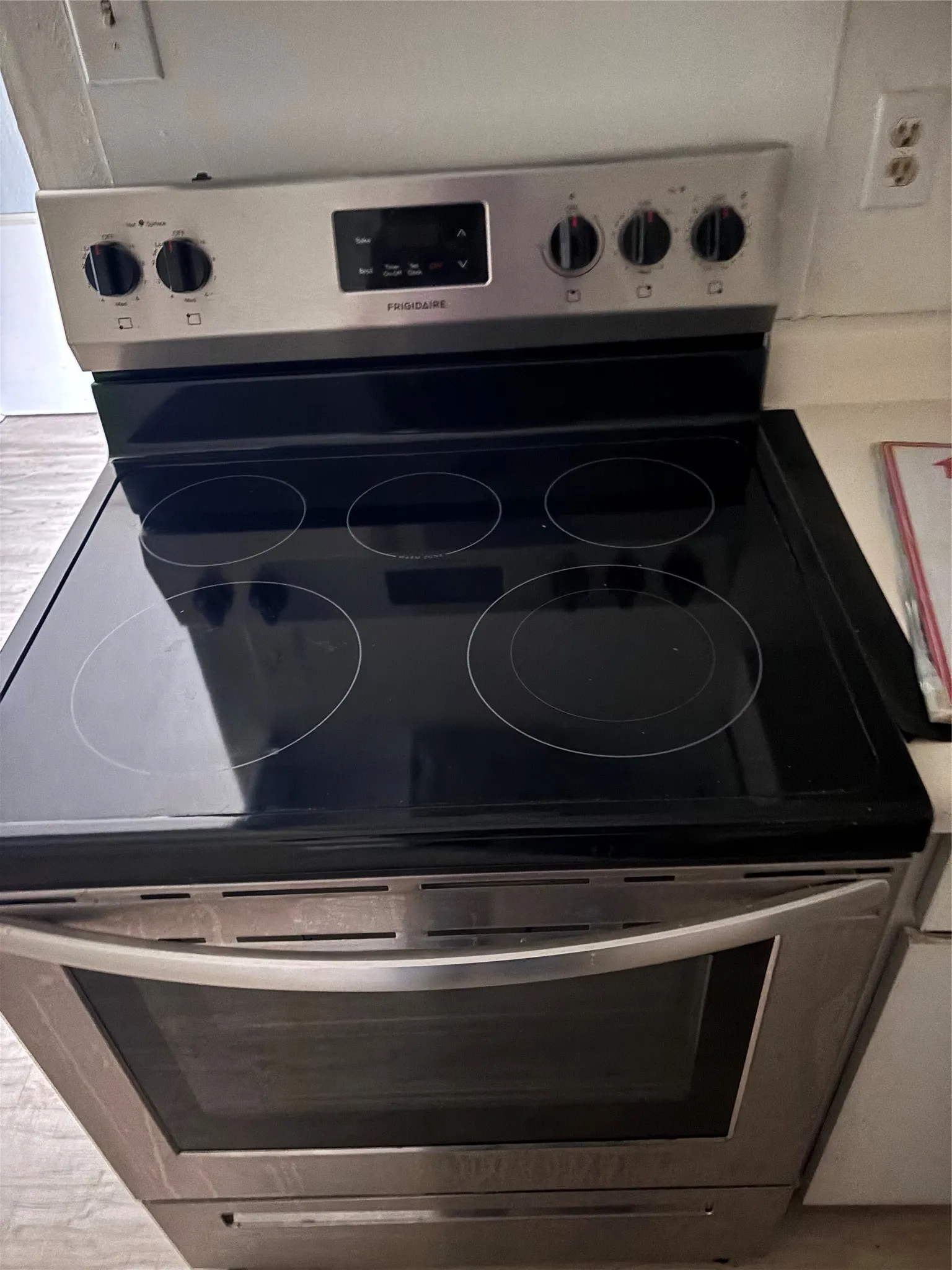 Stainless steel electric range with a black smooth cooktop and front controls