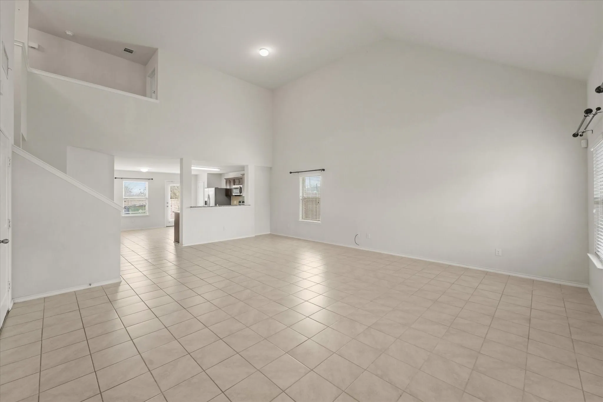 Vaulted ceiling, ceramic tile flooring, open concept layout, interior staircase, and upper-level architectural feature