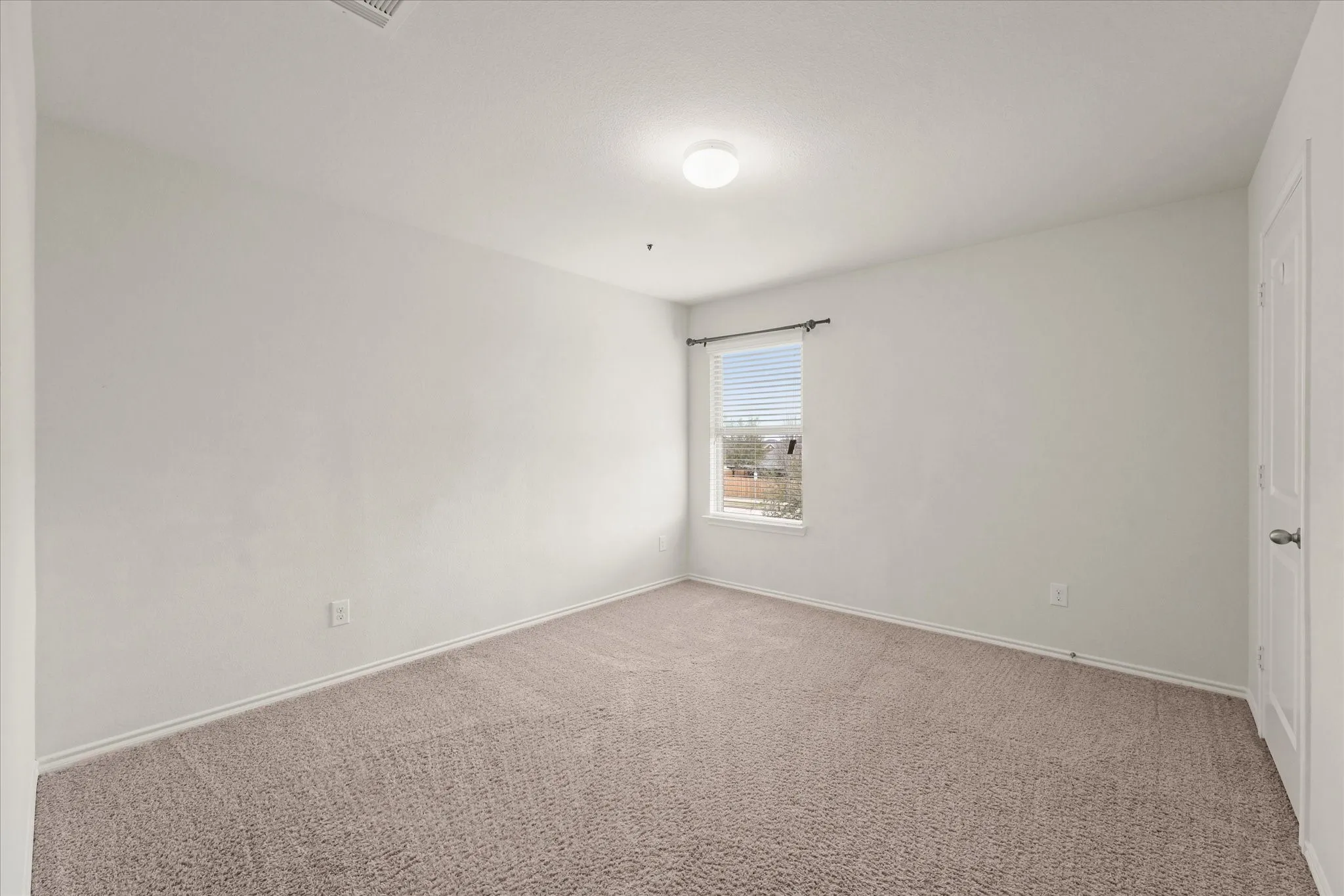 Carpeted room with a single window, white walls, and a flush-mount ceiling light fixture