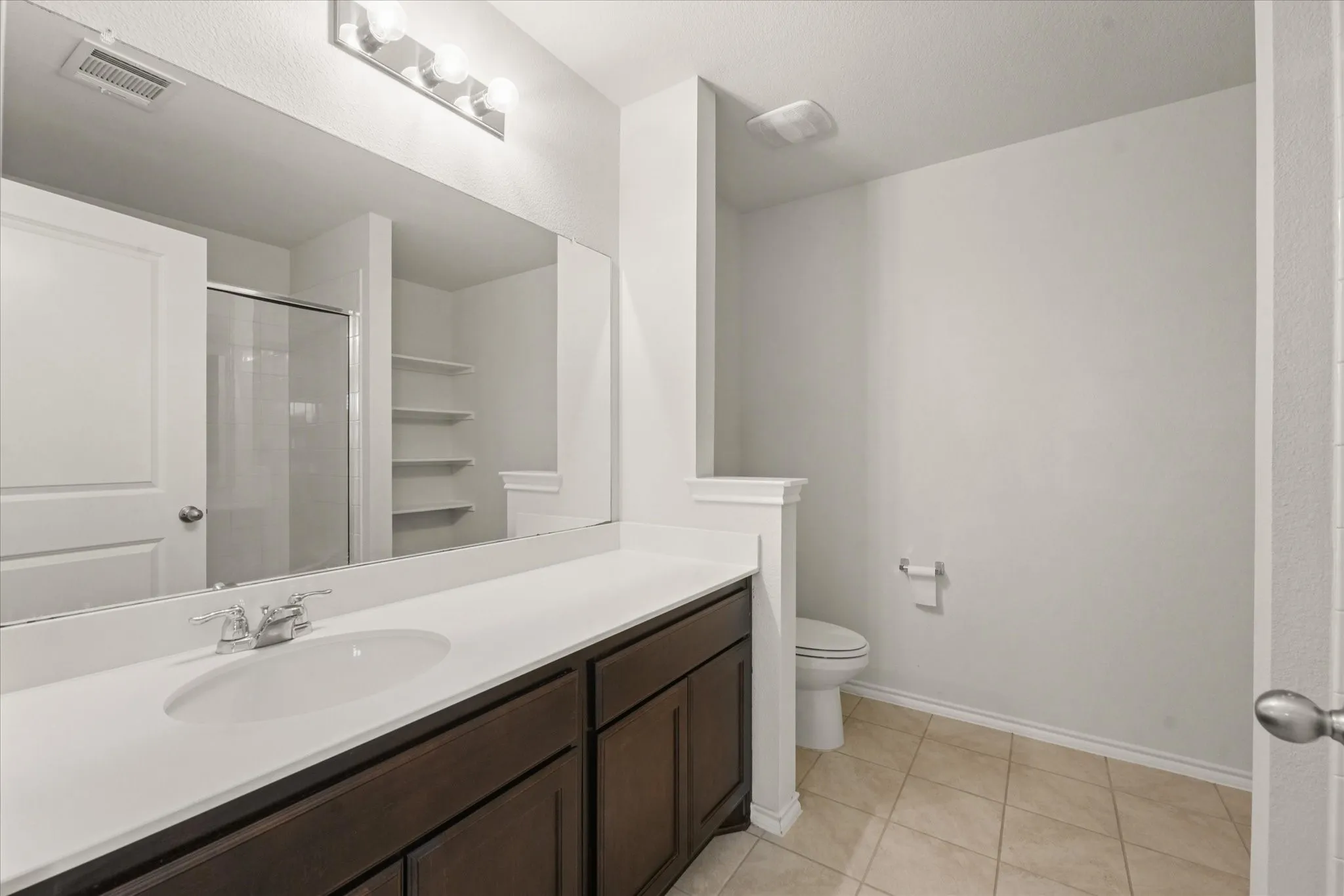White vanity with an integrated sink, polished chrome faucet, and expansive wall mirror
