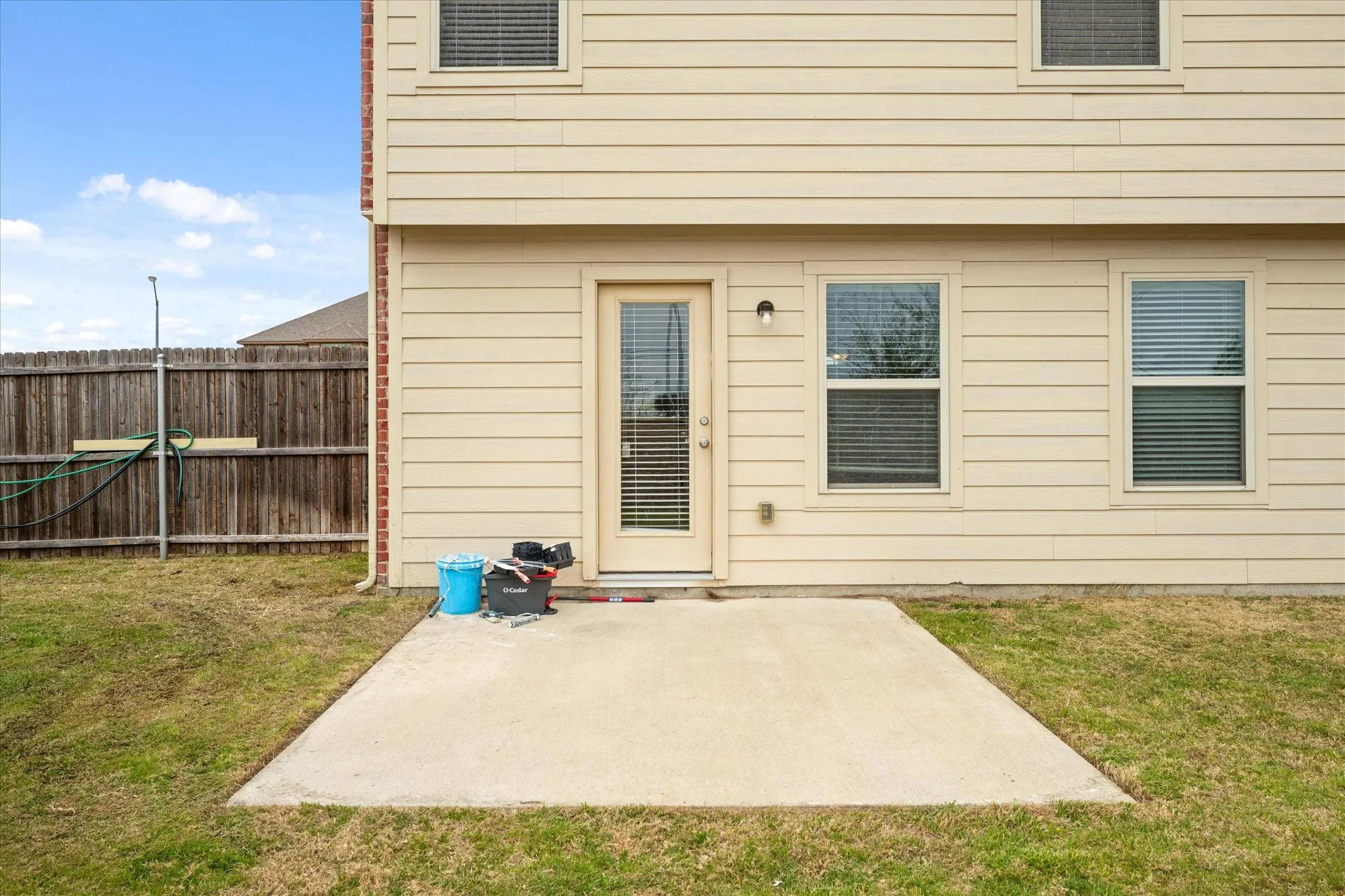 Concrete patio with direct outdoor access, a private wood fence, and a neutral siding exterior