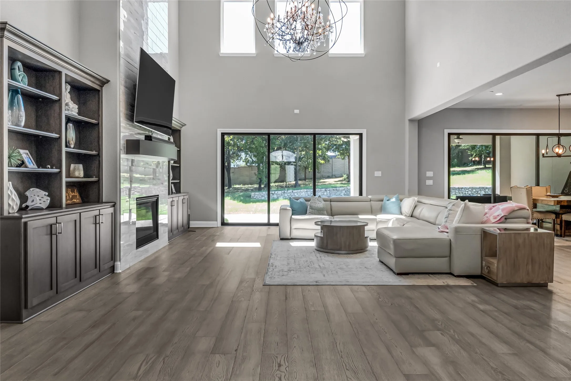 Vaulted ceilings with large windows, wood-finish flooring, built-in shelving, a fireplace, and sliding glass doors