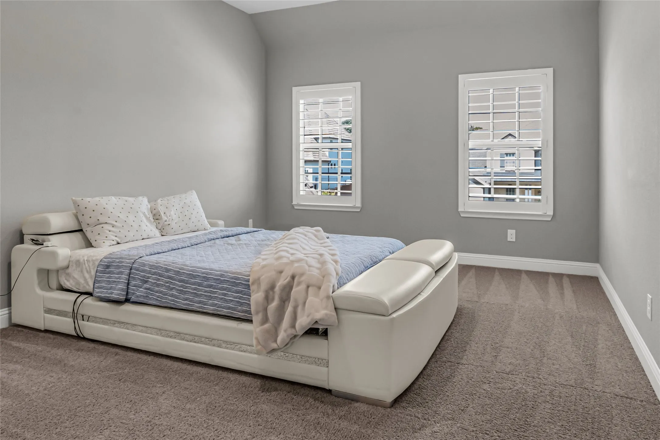 Two windows with plantation shutters, neutral tone walls, and carpeting