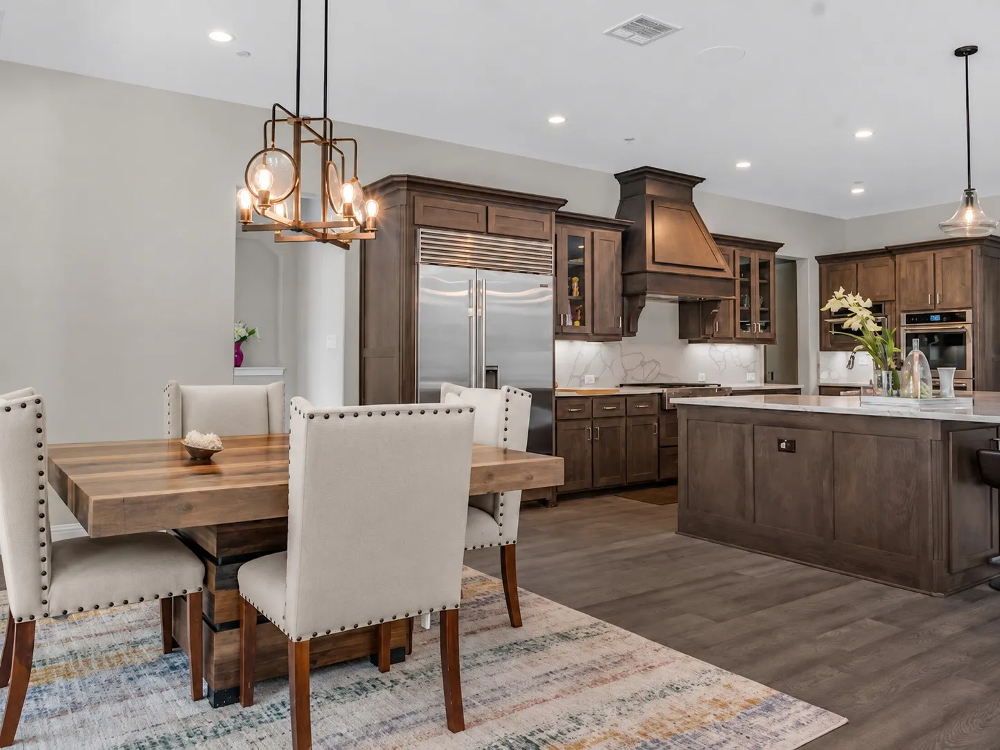Gourmet kitchen featuring wood cabinetry, integrated stainless steel refrigerator, and a large center island with a stone countertop