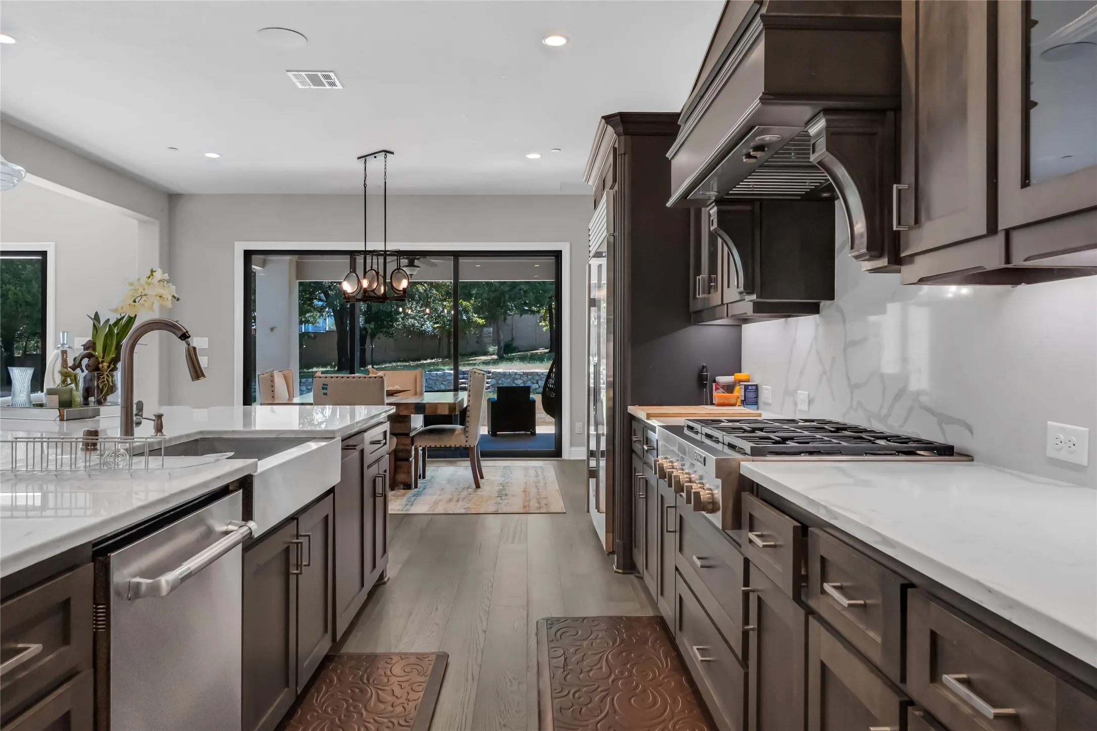 Gourmet kitchen with dark wood cabinetry, white countertops, built-in stainless steel appliances, and wood-finish flooring