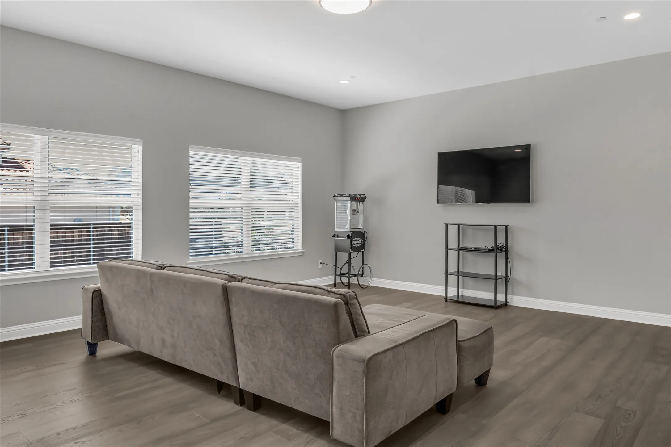 Recessed lighting, wood-finish flooring, two window openings, and wall-mounted television