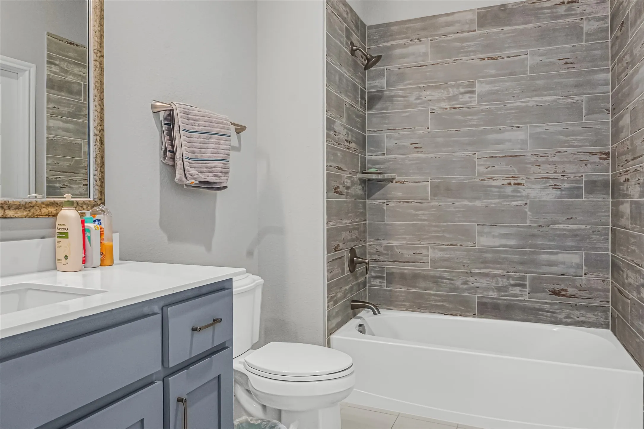 Built-in bathtub with subway tile surround, integrated showerhead, and wall-mounted faucet