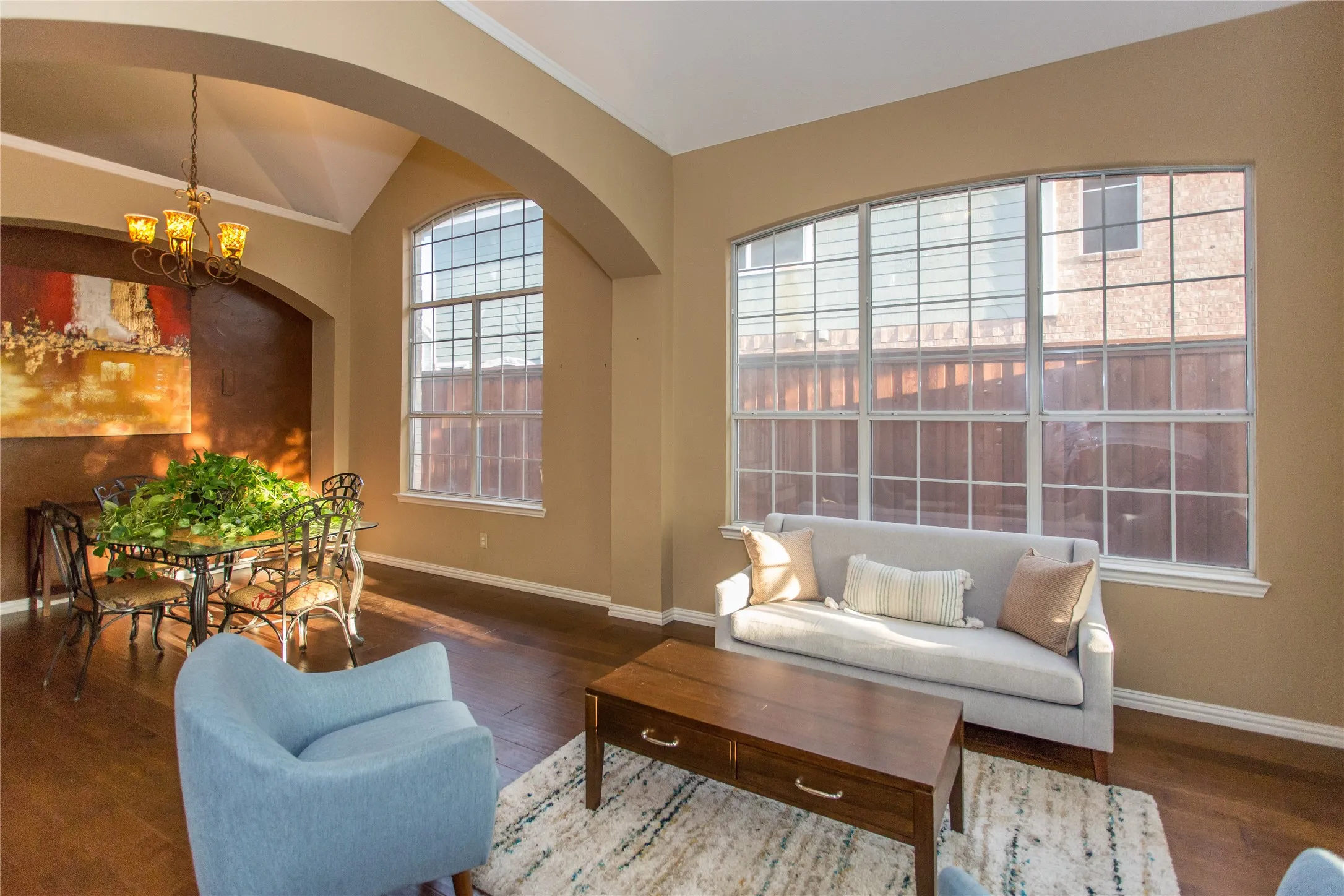 Hardwood-finish flooring, arched entryway, vaulted ceiling, multi-pane windows, and a decorative chandelier