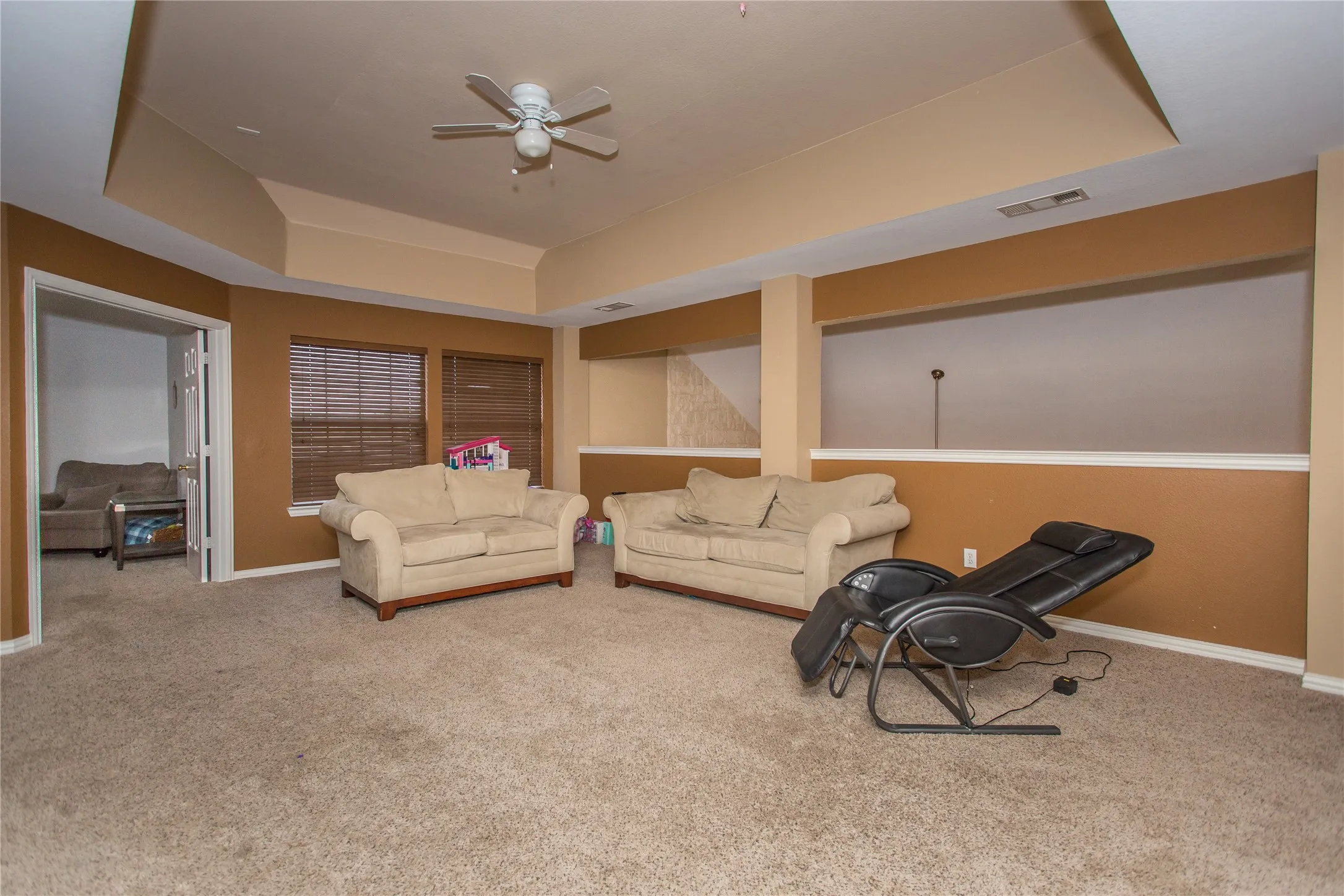 Carpeted room with a tray ceiling and ceiling fan
