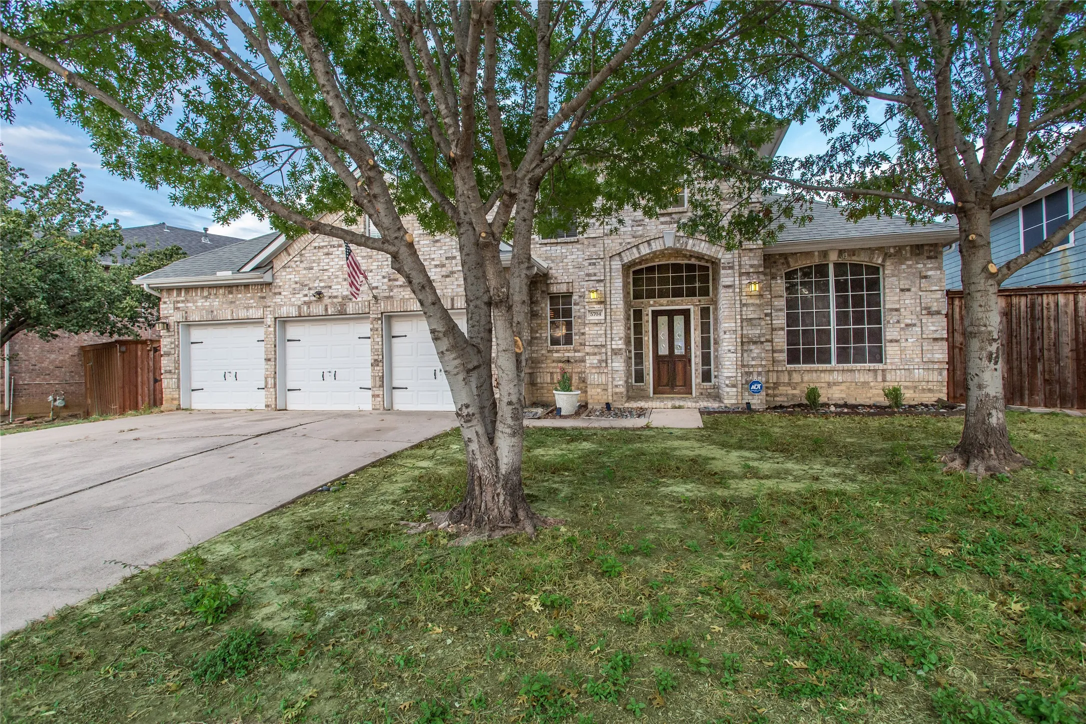 Stone facade with an arched entry, a three-car garage, and a concrete driveway