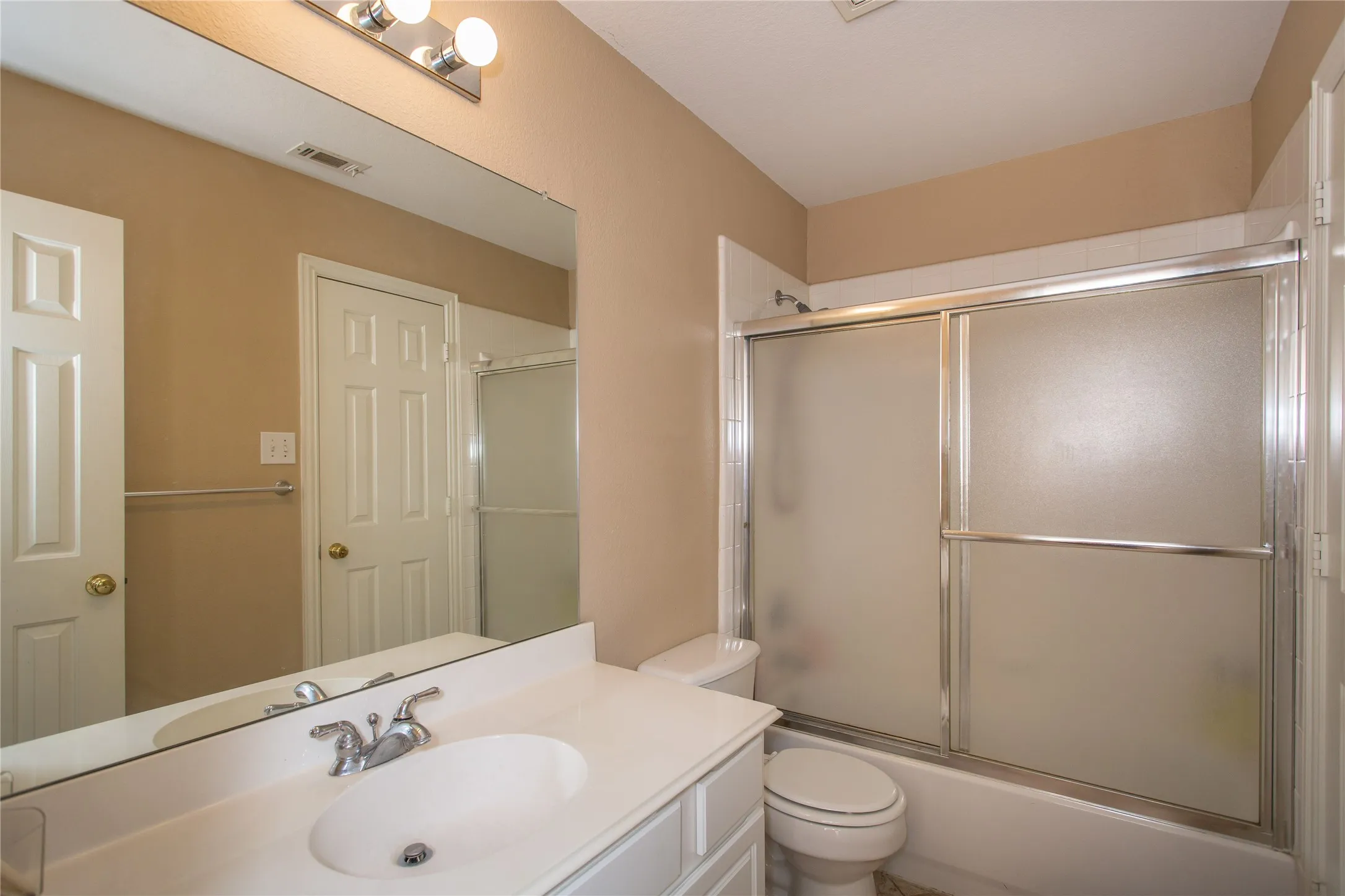 Vanity with an integrated sink, polished chrome faucet, and a wall-mounted mirror