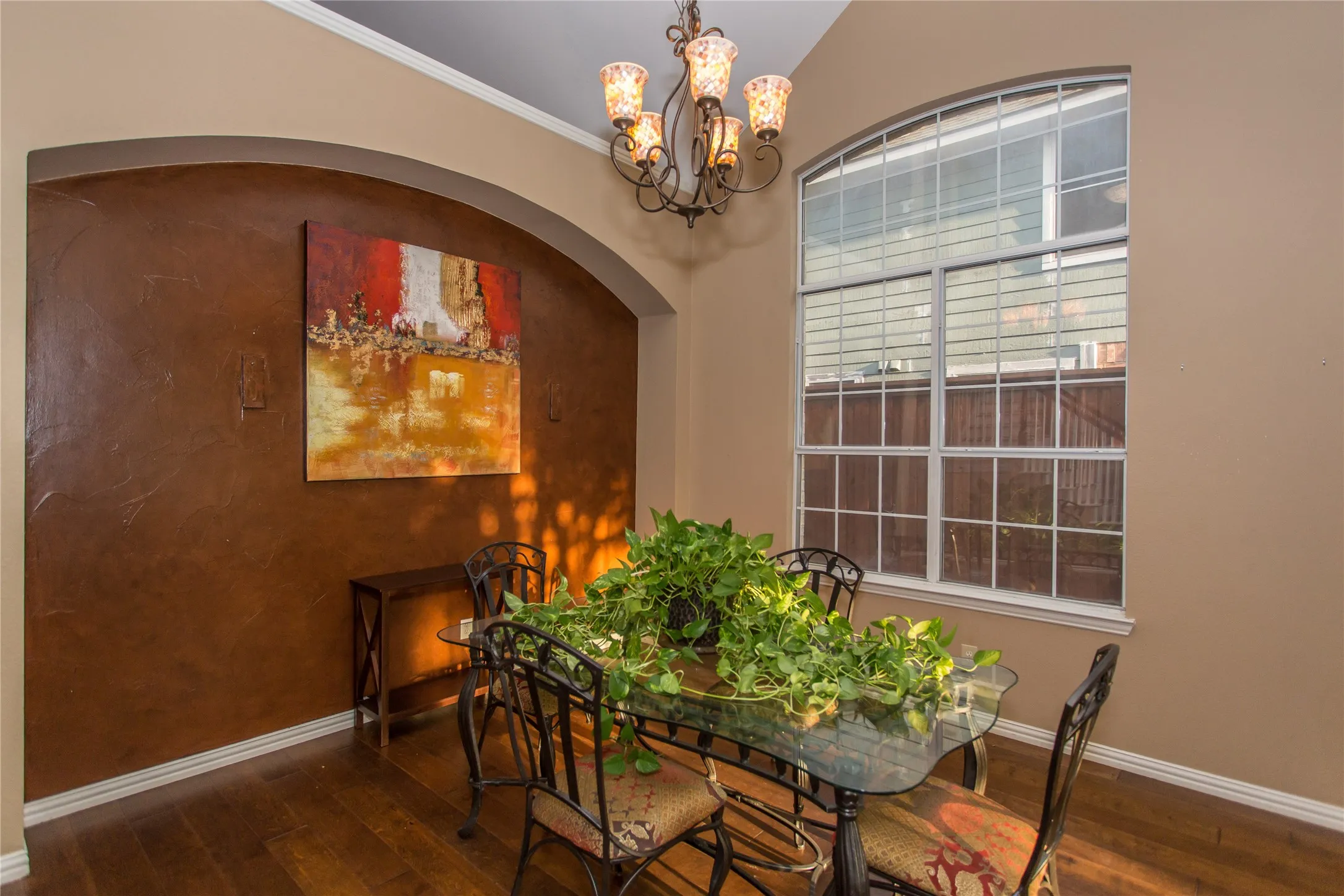Arched entryway, vaulted ceiling, wood-finish flooring, textured accent wall, and a large arched window