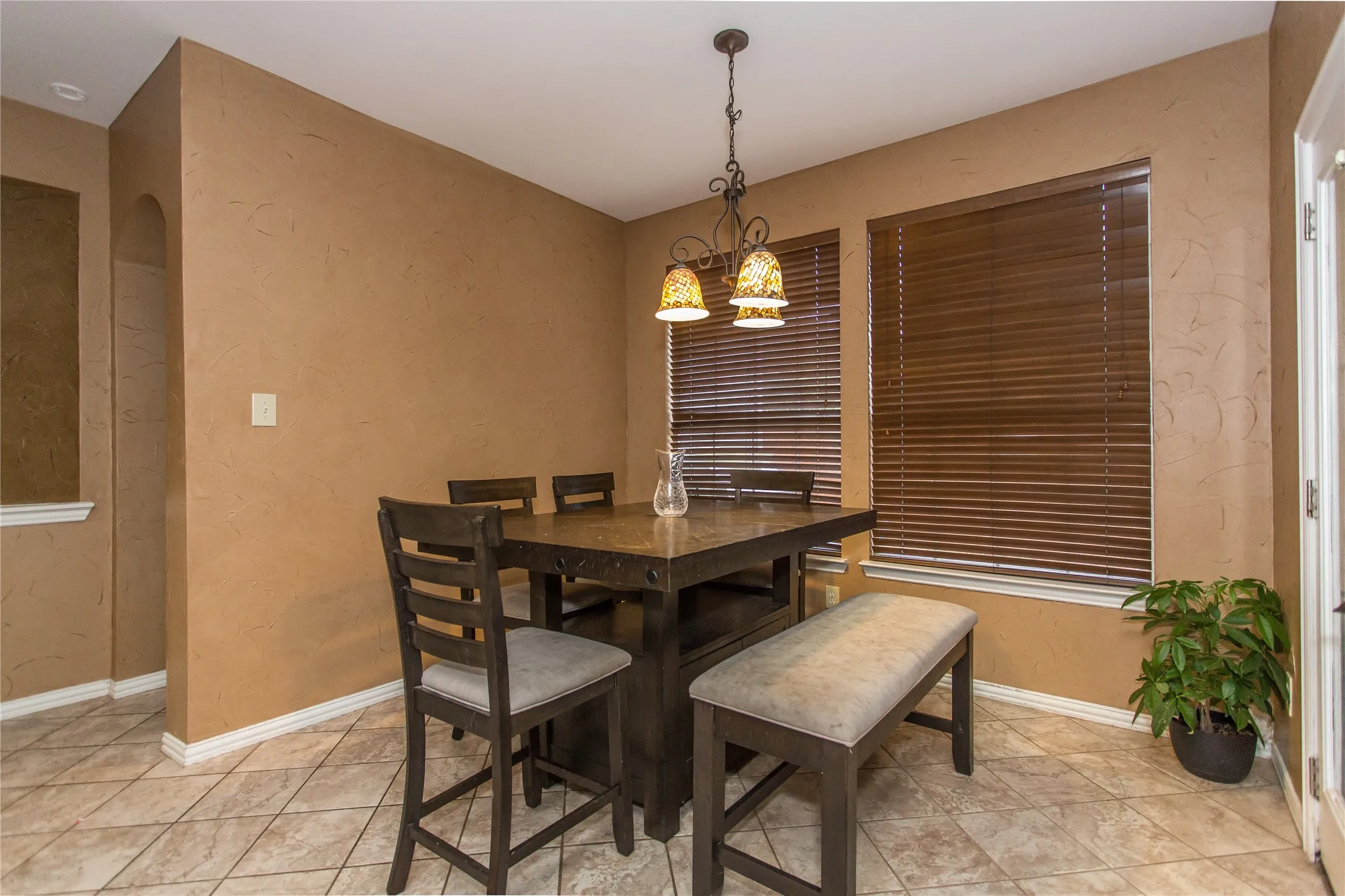 Dining area featuring textured walls, tile flooring, and a decorative chandelier