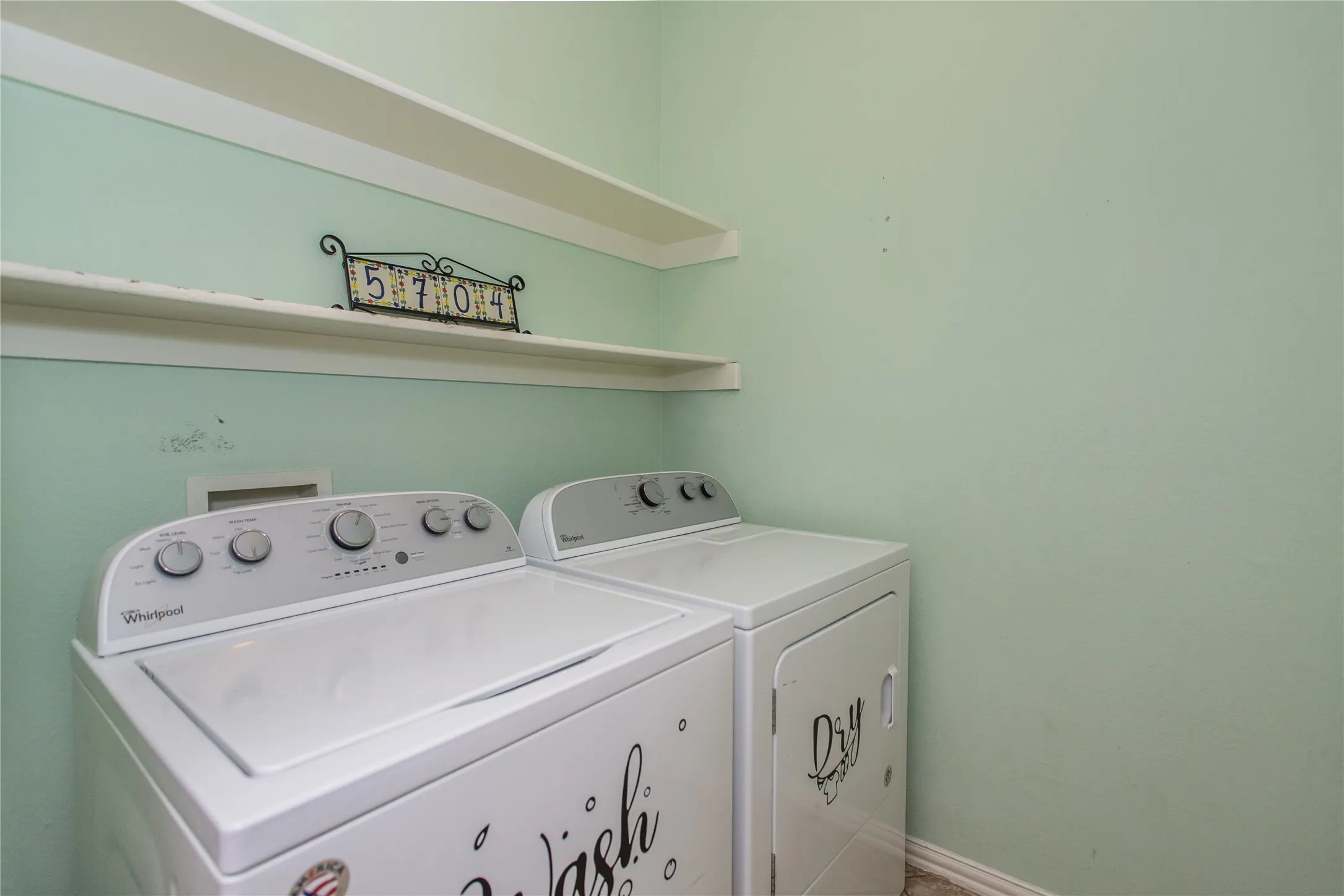 Laundry area featuring light green walls and built-in shelving