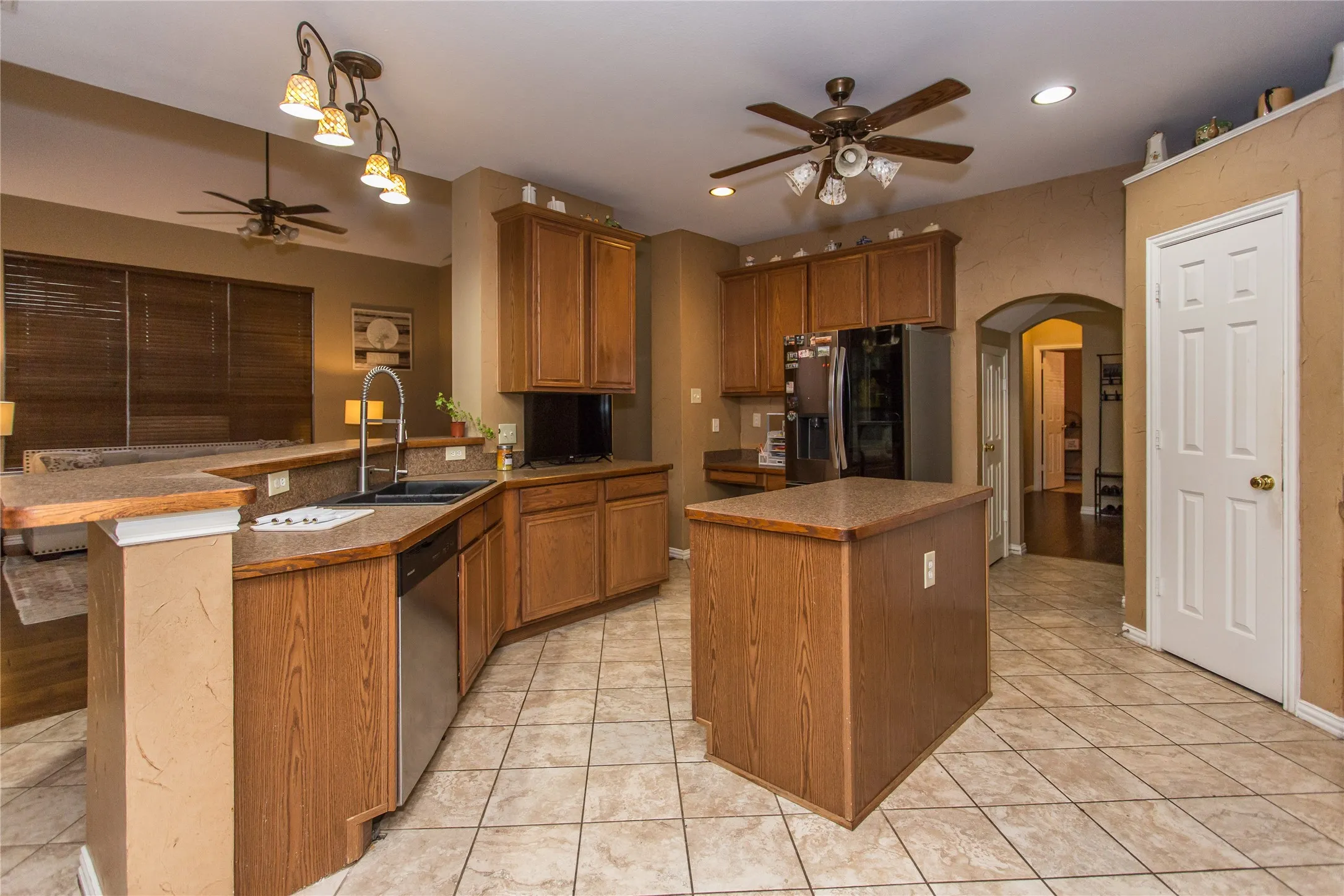 U-shaped kitchen featuring wood-finish cabinetry, a central island, and tile flooring
