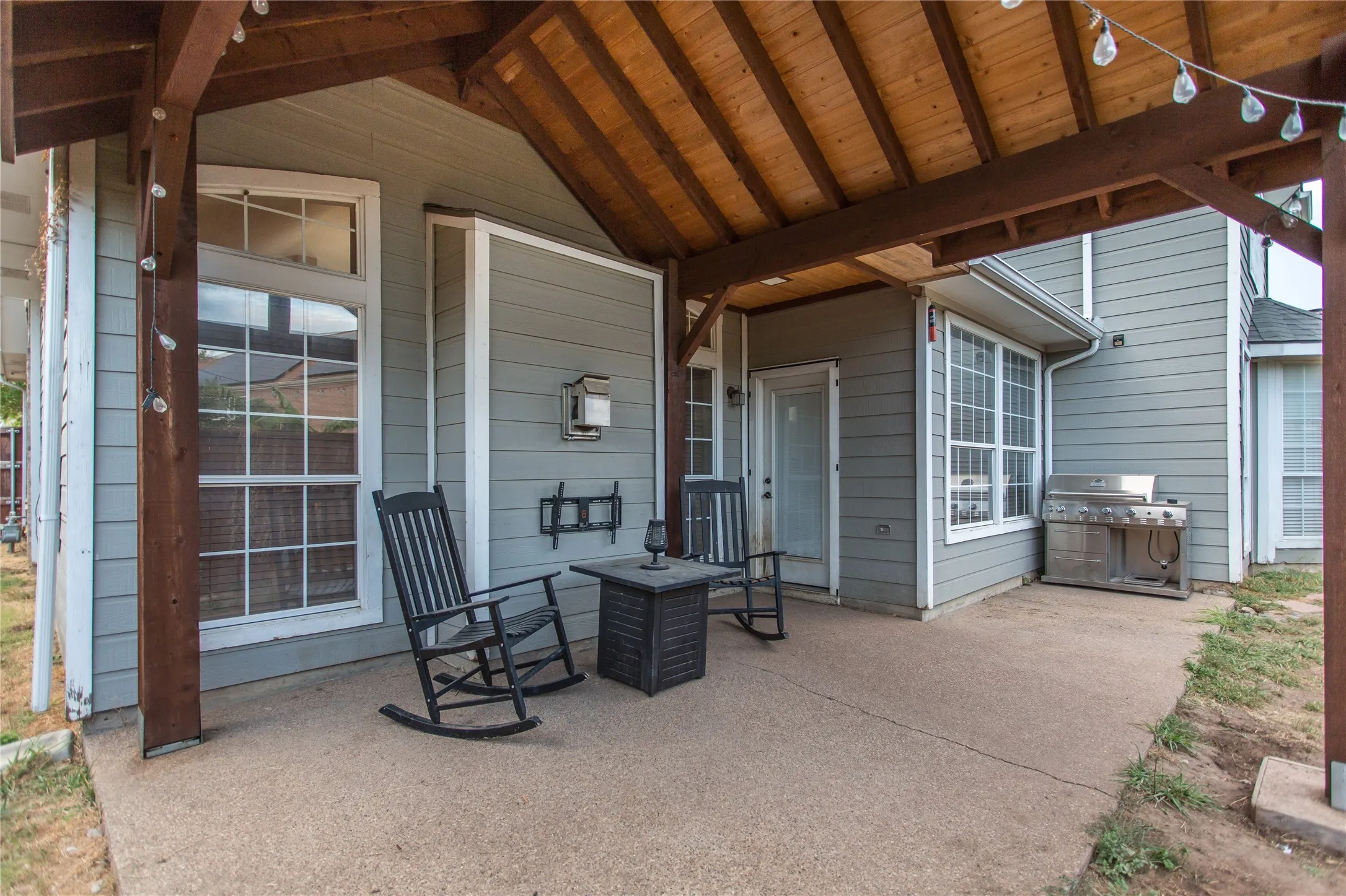 Covered patio with a wood-plank ceiling, concrete flooring, and gray siding