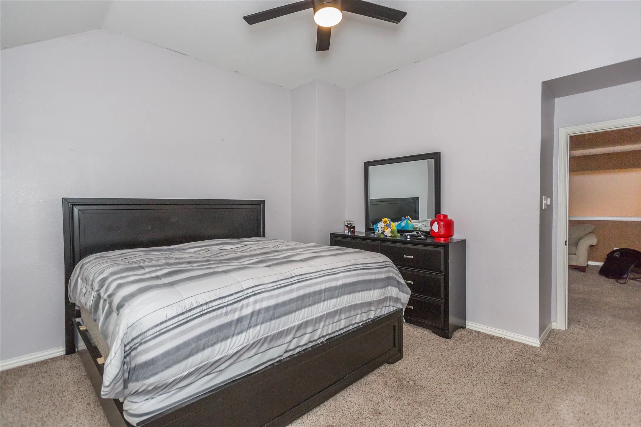 Vaulted ceiling, ceiling fan with integrated lighting, neutral wall paint, and carpeted flooring