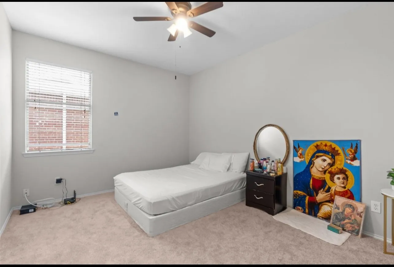 Carpeted room featuring a ceiling fan with integrated lighting, a window with blinds, and light-colored walls