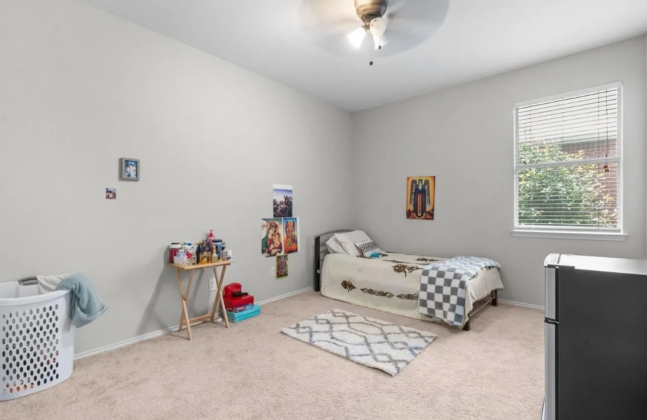 Neutral wall paint, ceiling fan with integrated lighting, window with blinds, and carpeted flooring