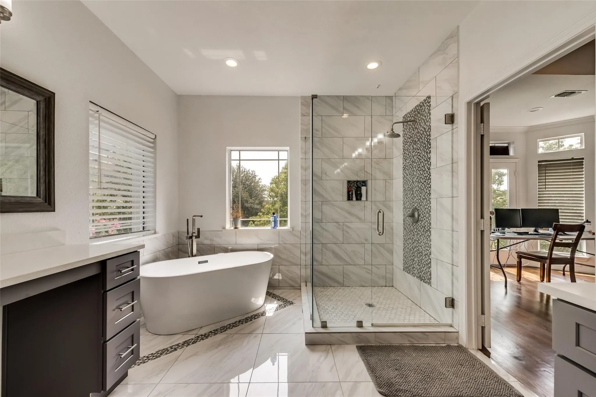Spacious bathroom featuring a freestanding tub, a glass-enclosed shower with tile surround, a built-in vanity with countertop, and tile flooring