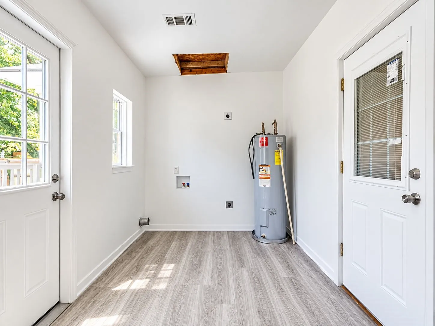 Laundry area featuring wood-finish flooring, white walls, and a water heater