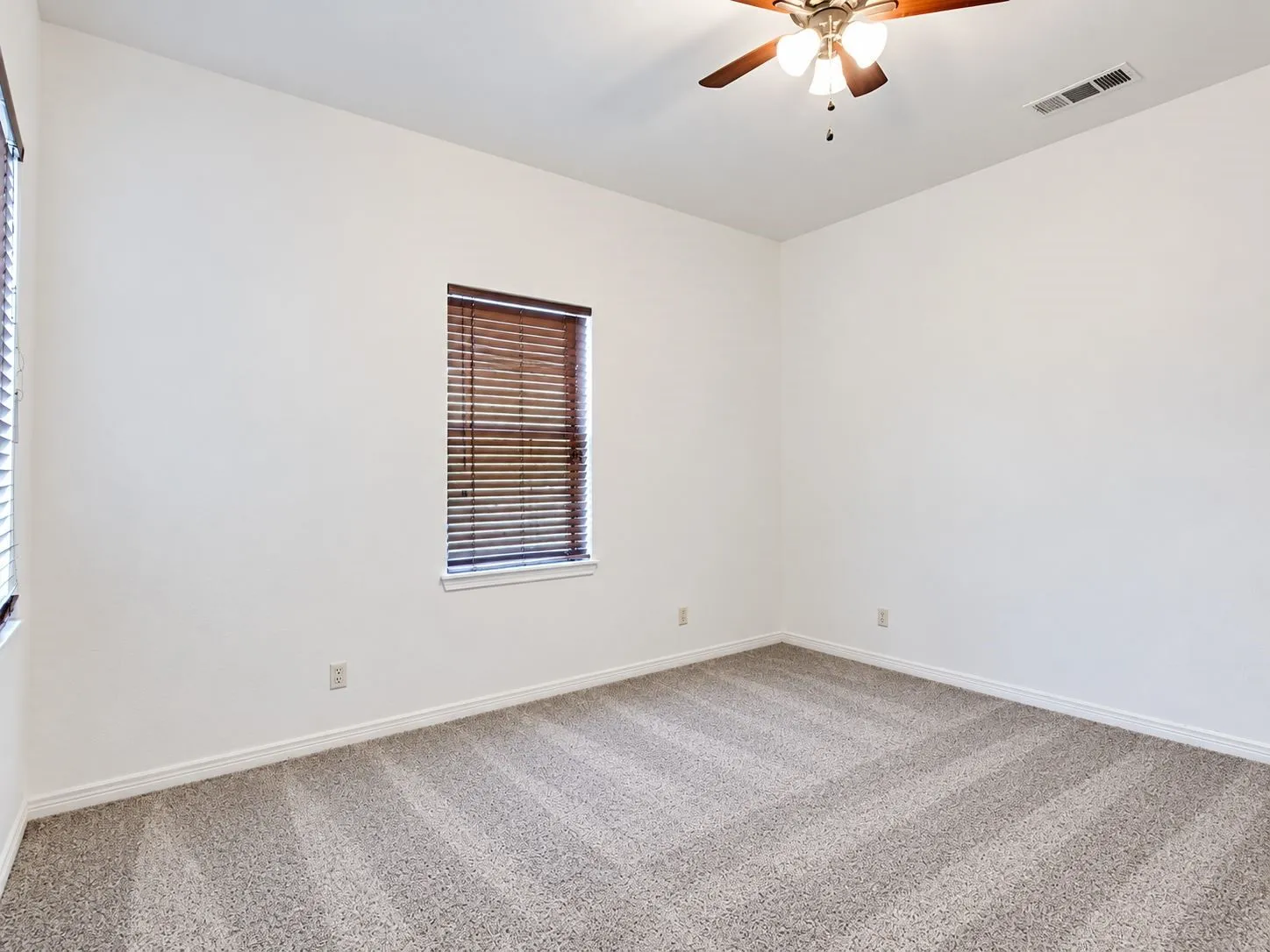 Neutral wall finishes, window with wood-tone blinds, and a ceiling fan with light fixture