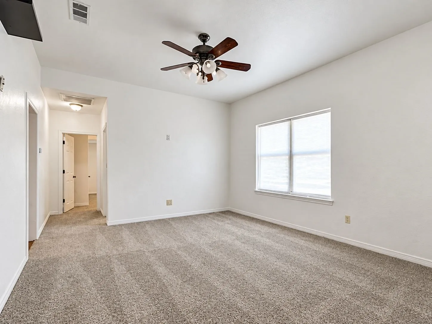 Neutral-toned carpeting, white walls, and a ceiling fan with integrated lighting