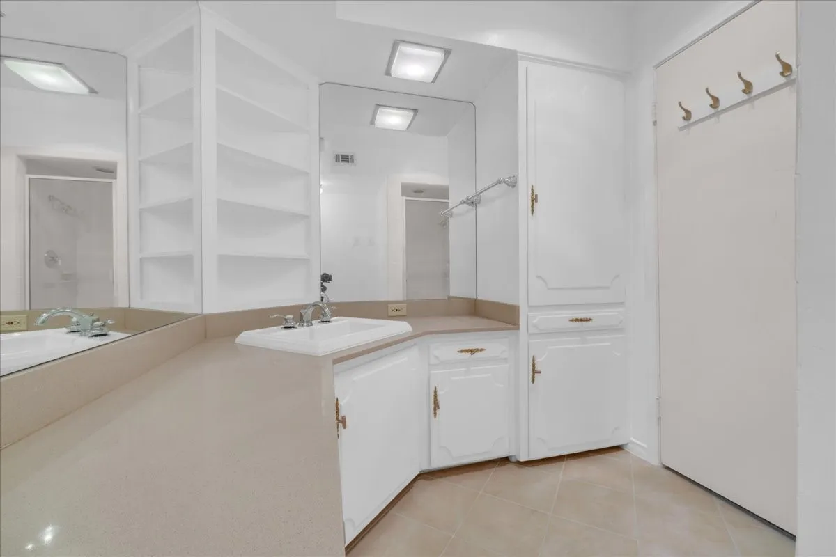 Bathroom featuring a vanity with an integrated sink, built-in shelving, white cabinetry, and wall-mounted mirrors