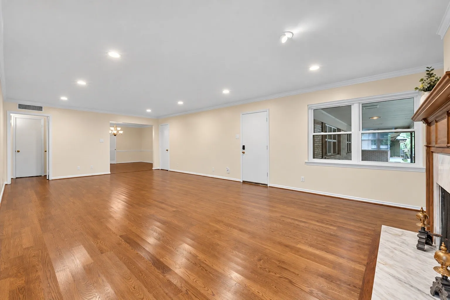 Wood-finish flooring throughout, recessed lighting, white trim, and a fireplace with a marble hearth