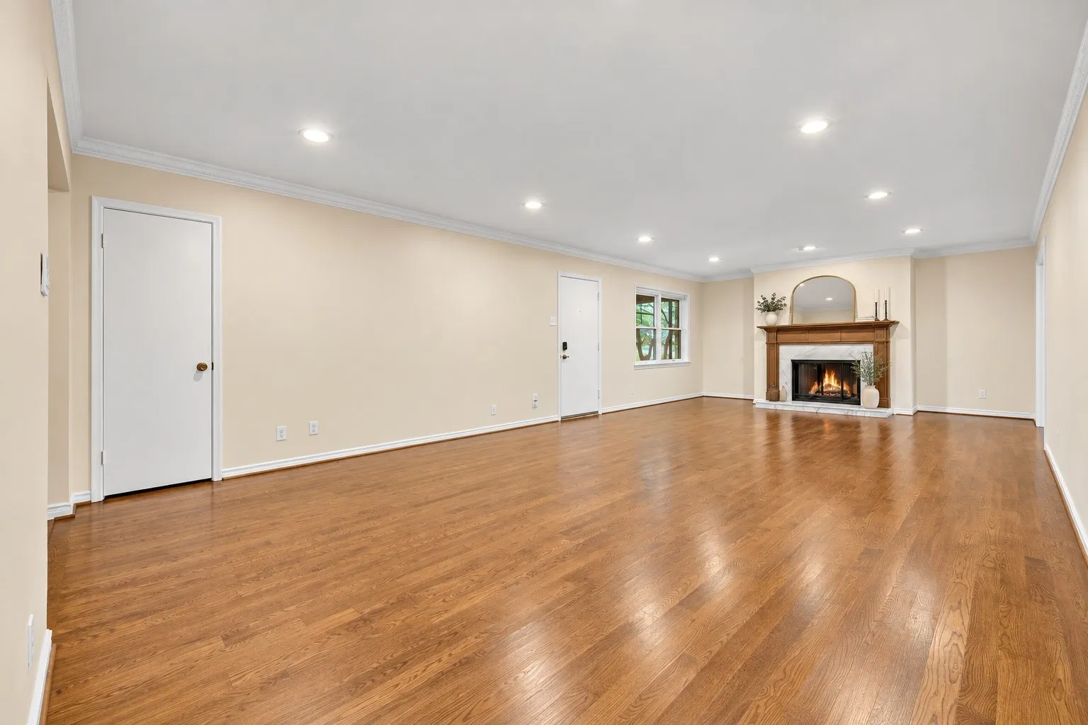 Expansive room featuring wood-finish flooring, a traditional fireplace with a wood mantle and hearth, recessed lighting, and crown molding