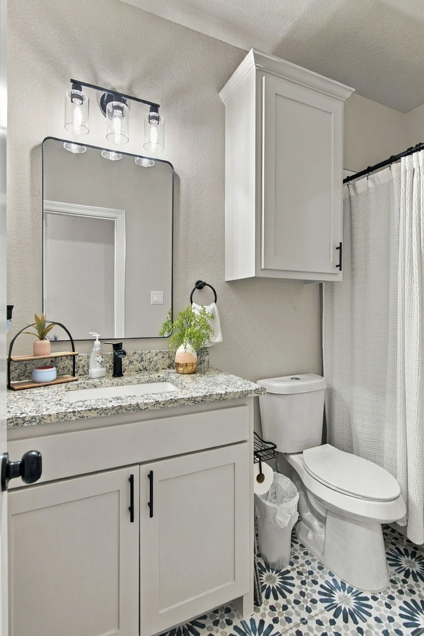 Vanity with a granite-style countertop, undermount sink, and matte black faucet