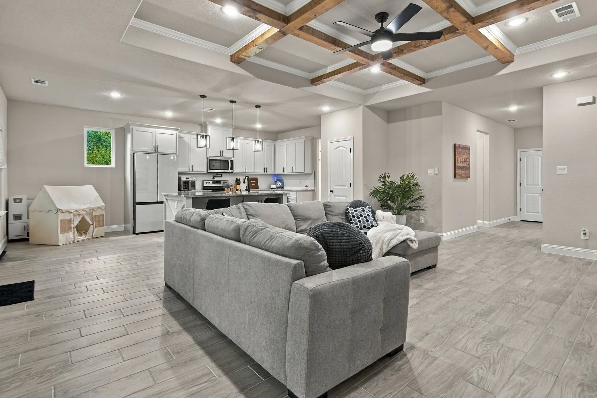 Tray ceiling with exposed wood beams, ceiling fan, recessed lighting, wood-finish flooring, and light-toned walls