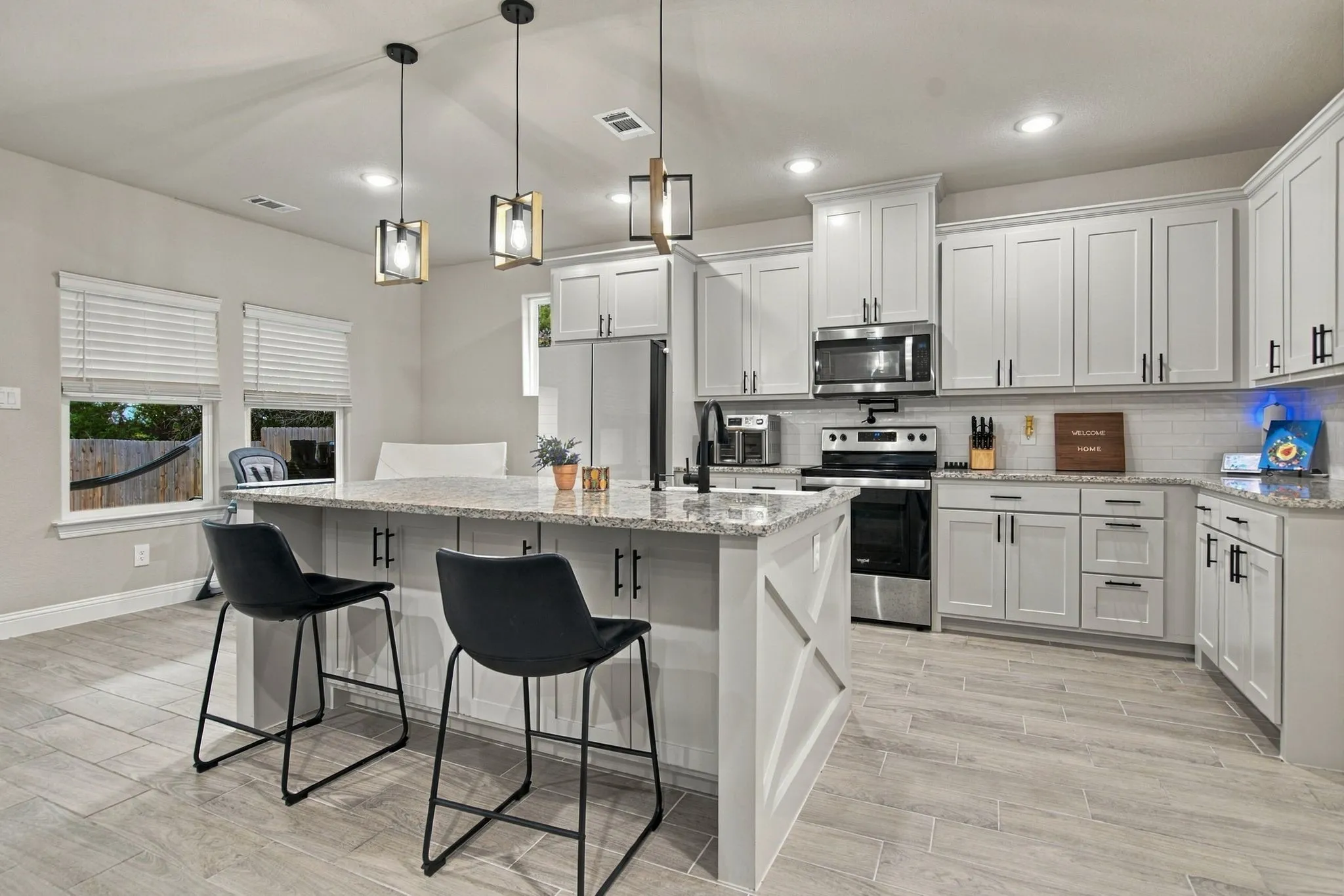 Kitchen featuring stainless steel appliances, light gray cabinetry, a central island with a granite countertop, and wood-finish flooring