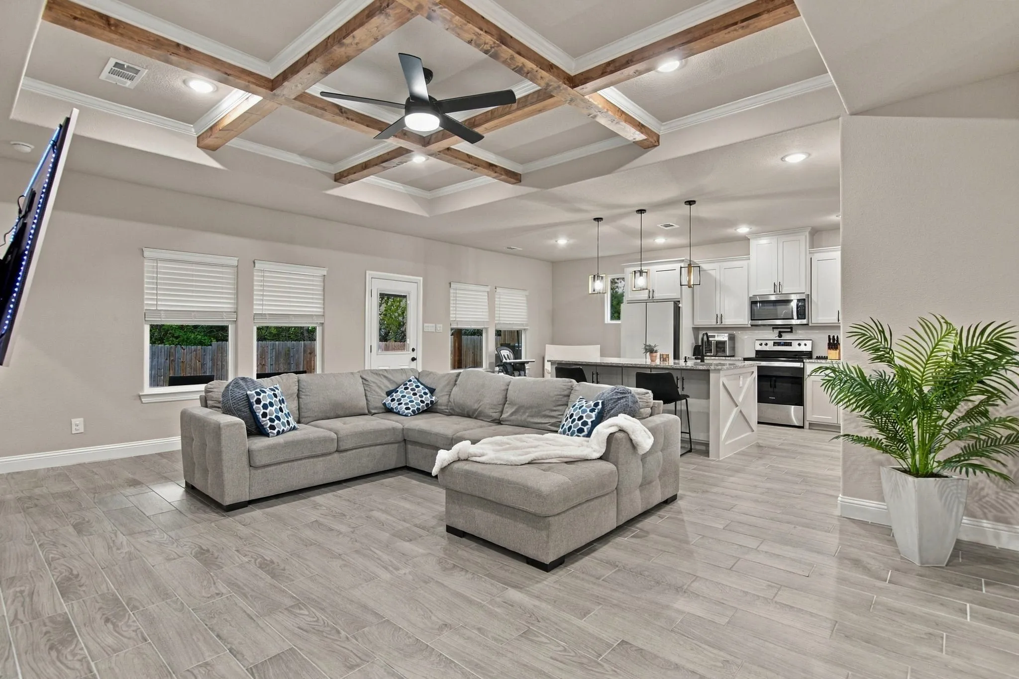 Coffered ceiling with exposed wood beams, recessed lighting, wood-finish flooring, white cabinetry, and stainless steel appliances