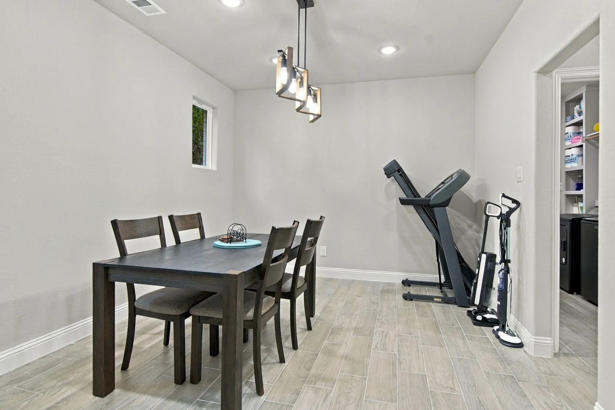 Recessed lighting with a contemporary chandelier, light-toned walls, and wood-finish flooring