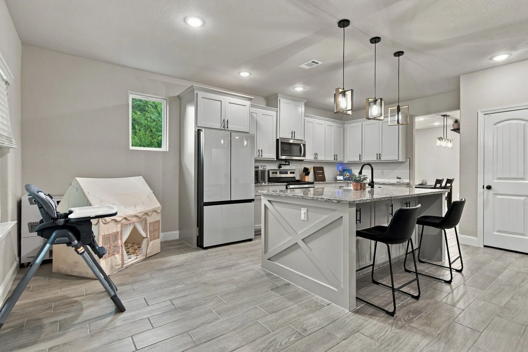 Contemporary kitchen featuring light wood-finish flooring, white cabinetry, stainless steel appliances, a center island with bar seating, and recessed lighting