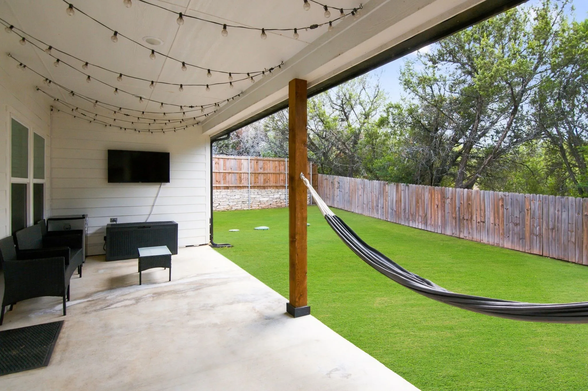 Covered patio featuring a wood support column and string lighting