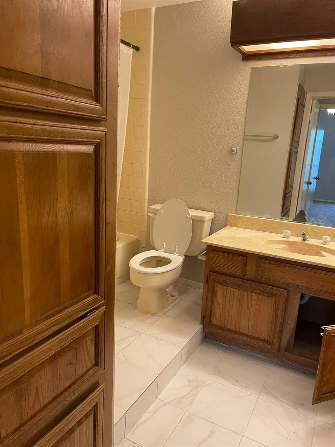 Wood-finish cabinetry, tile flooring, vanity with integrated sink, and a full-size bathtub